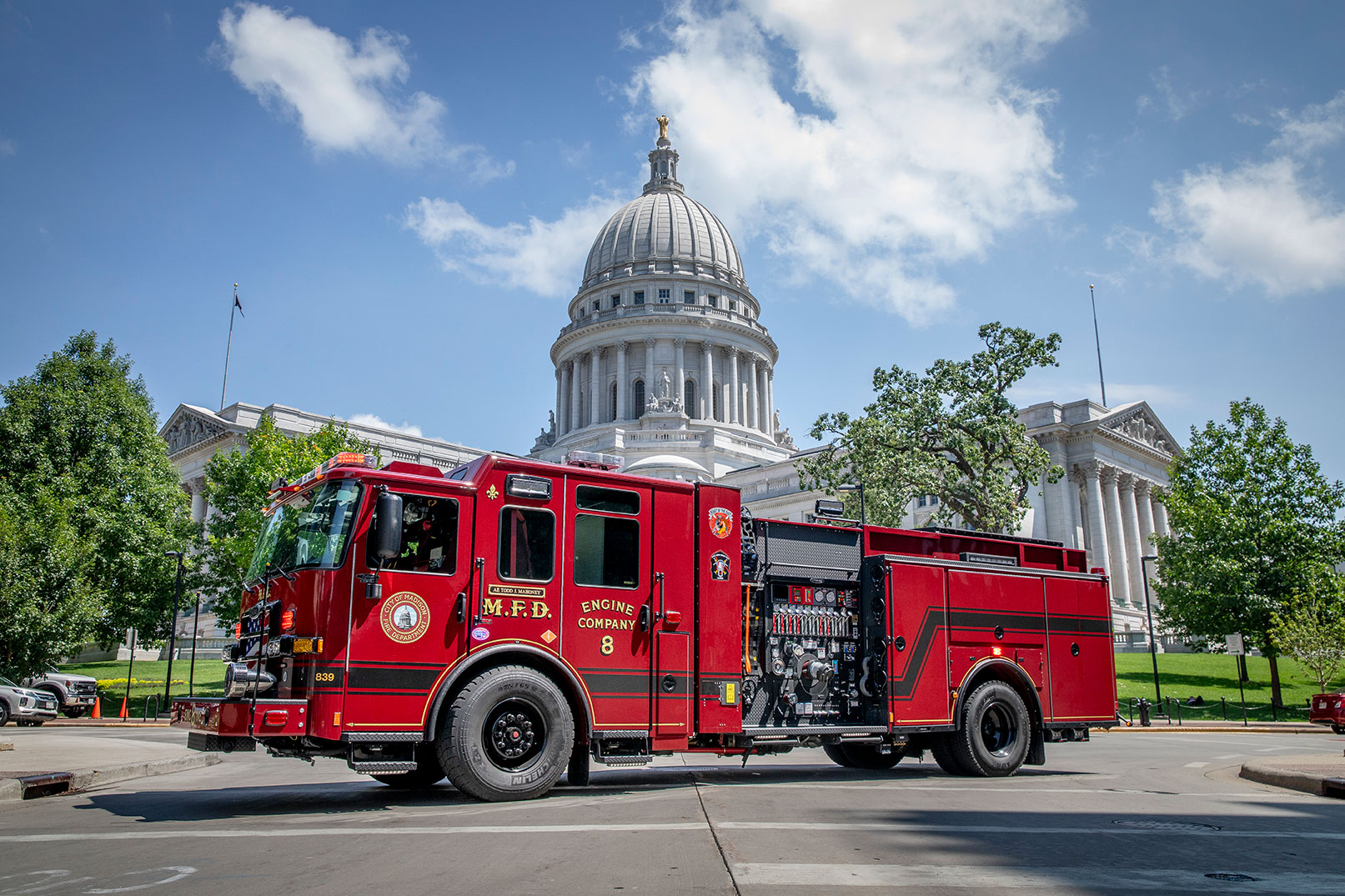 The drivers side of an Enforcer Volterra Electric Fire Truck parked in front of the capitol building in Wisconsin on sunny day.