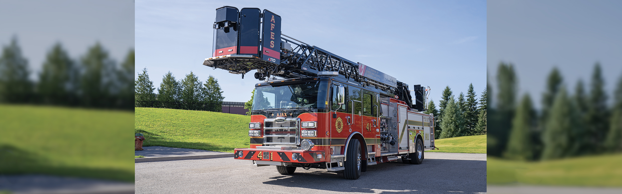 An Enforcer 110 Ascendant Aerial Platform parked in a parking lot in front of a hill with green grass and trees.