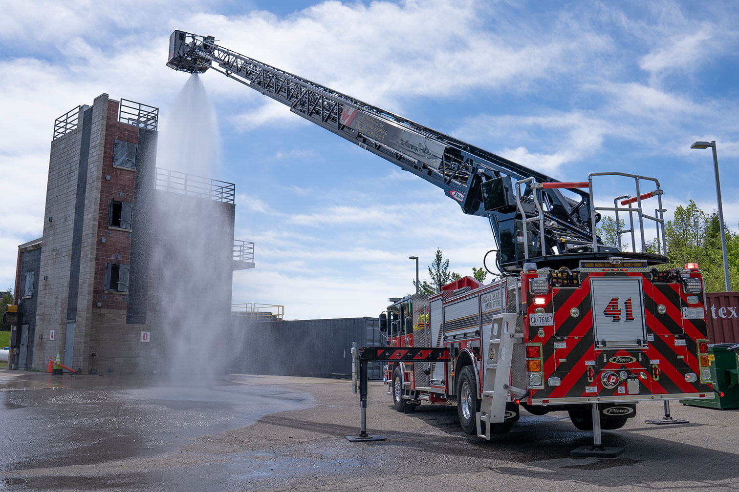 The rear of an Enforcer 110 Ascendant Aerial Platform with water spraying from the aerial waterway onto a fire training facility.