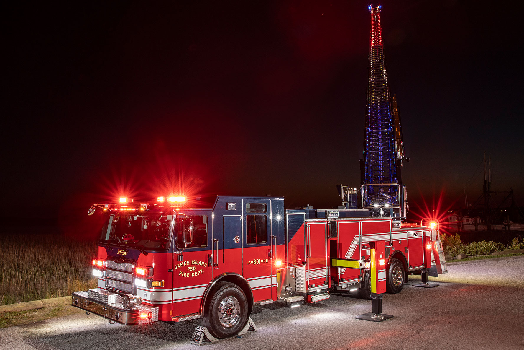 An Enforcer 107 Ascendant Aerial Ladder parked with the aerial ladder up showing red, white and blue rung lighting.