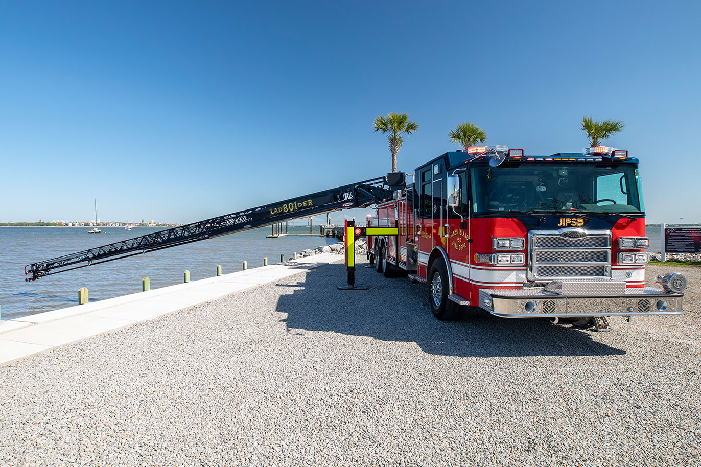 The front of an Enforcer 107 Ascendant Aerial Ladder with the aerial extended over a bay with boats in the background.