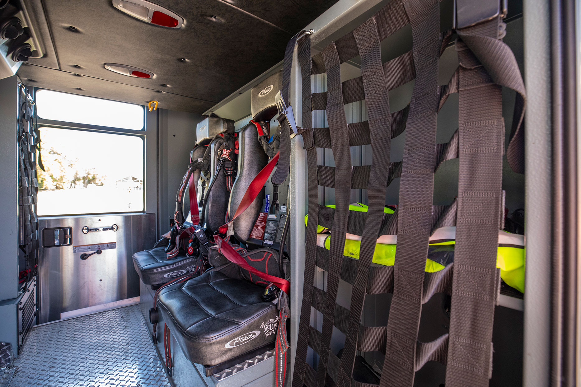 The inside crew cab of a fire truck with two seats with SCBA holders for firefighters and compartments filled with equipment.