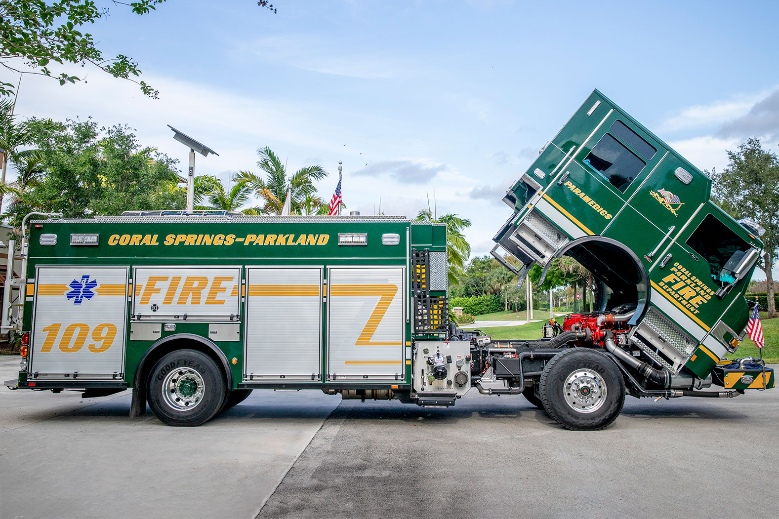 The officers side of an Impel PUC Pumper fire truck parked in a parking lot with the cab tilted showing the engine.