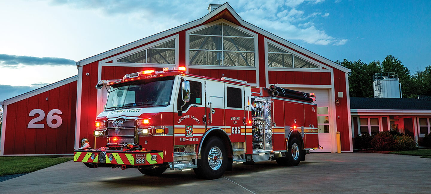 Pierce Velocity custom fire truck chassis parked outside in front of fire station. 