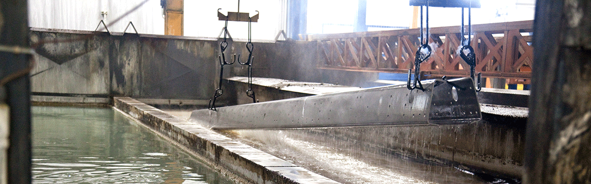 Metal equipment for a Pierce fire truck submerging into a coating solution during the E-Coat fire truck corrosion protection process. 