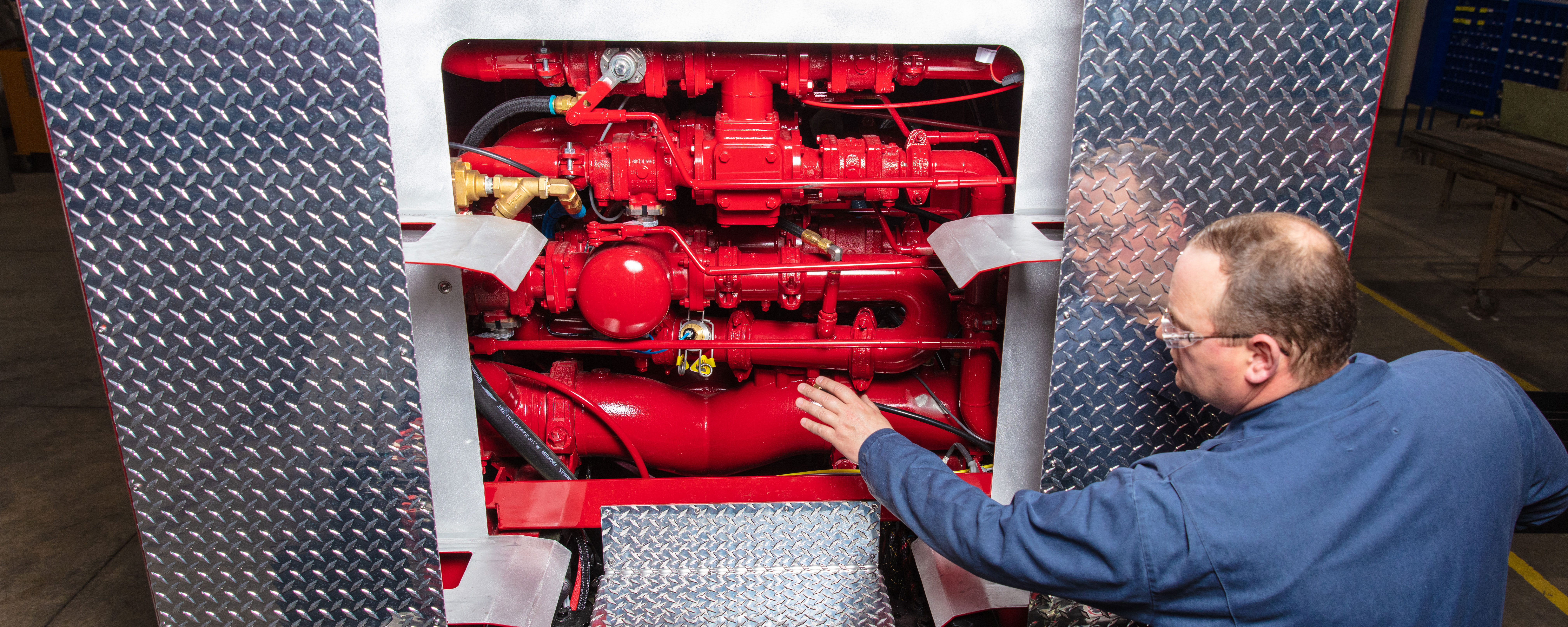 A man servicing the interior configuration on a Pierce Fire Truck. 