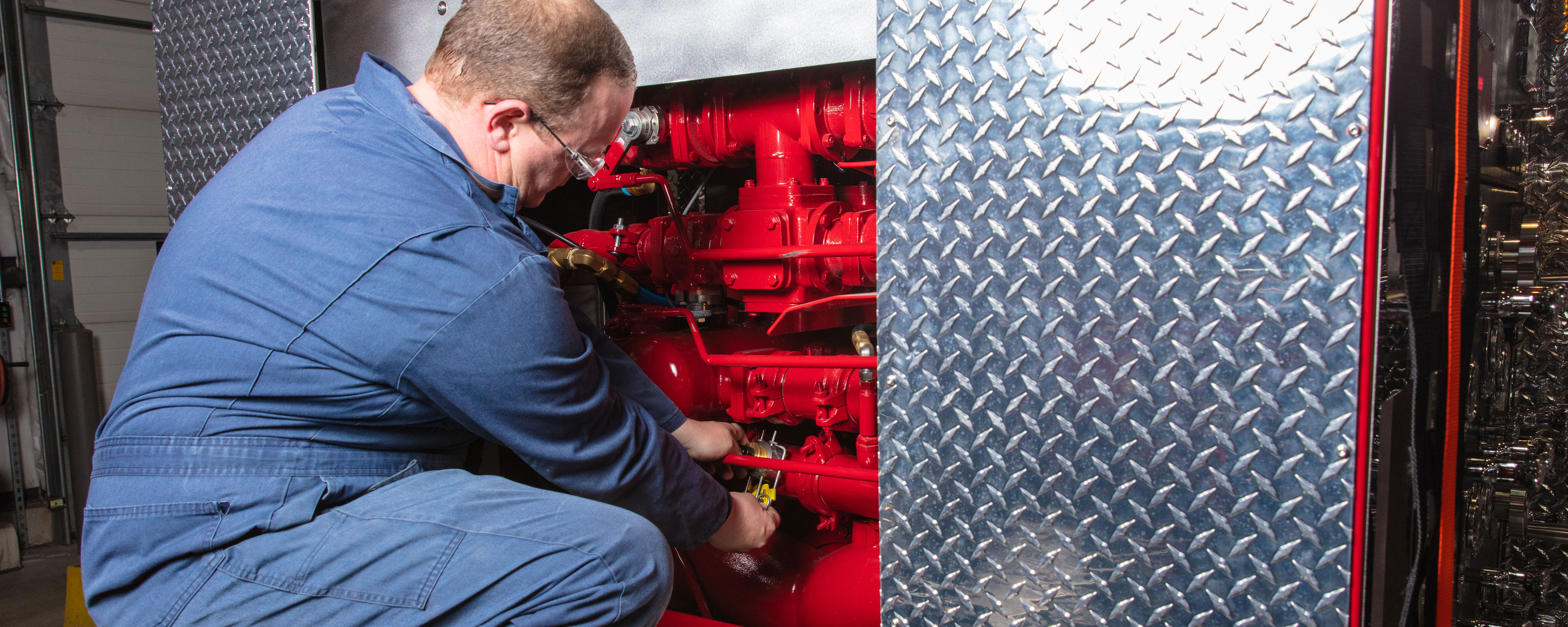 A man servicing Speedlays on a Pierce Fire Truck. 