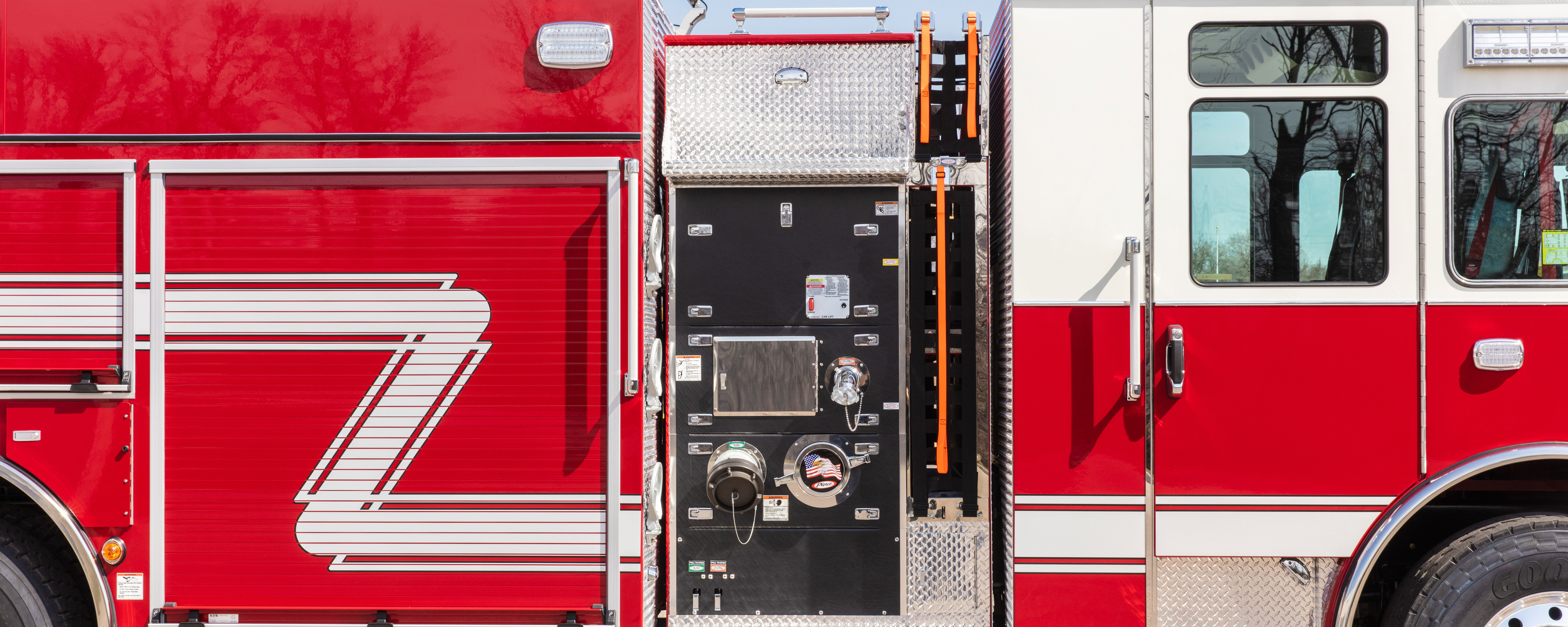 Side pump panel on the officer’s side of a Pierce Fire Truck parked outside on a sunny day. 