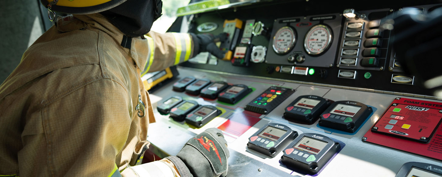 Firefighter in an enclosed Top Mount pump panel on a Pierce Fire Truck. 