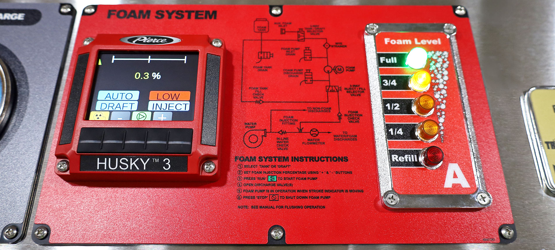 A red digital foam system controller on the pump panel of a fire truck.