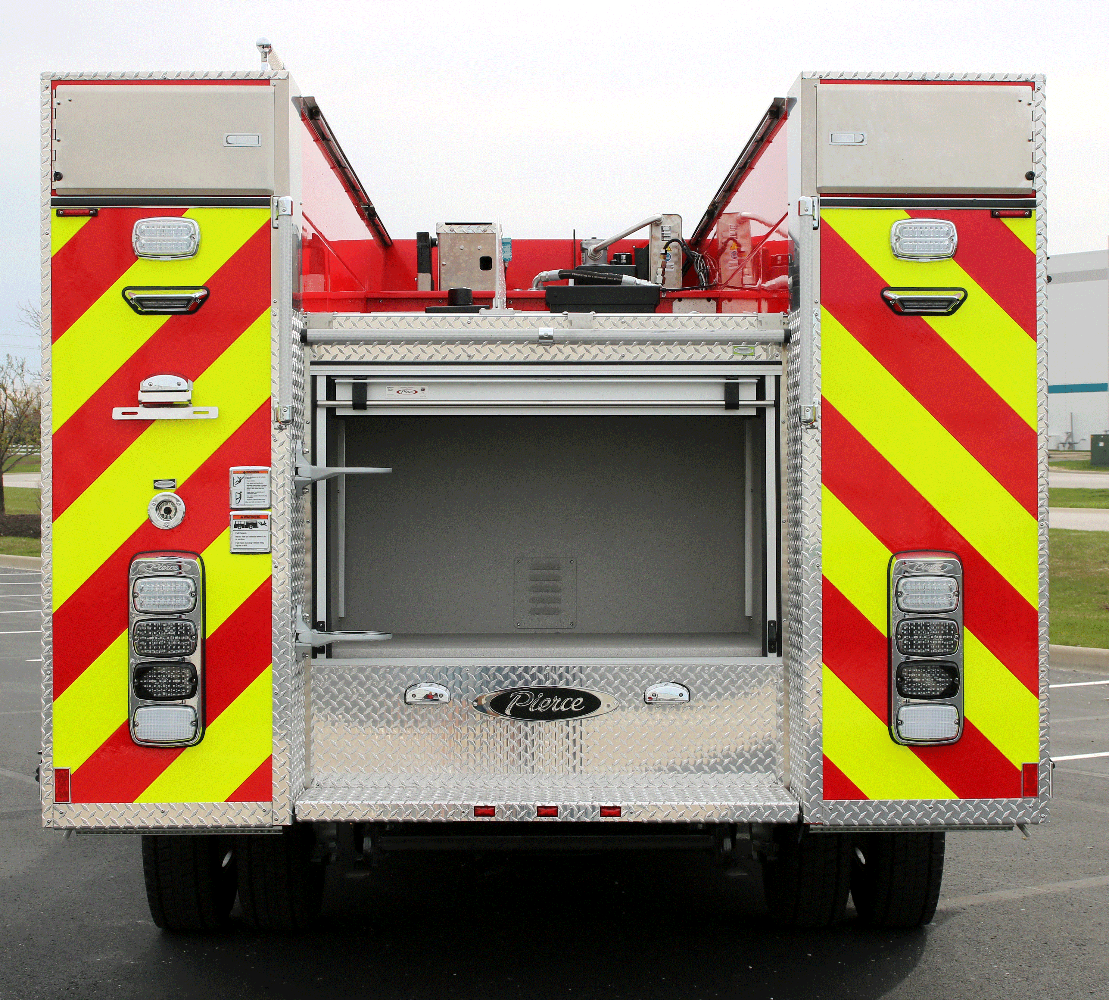 Rear exterior of Pierce Ford commercial fire truck chassis with back rolling door open to show storage configuration. 