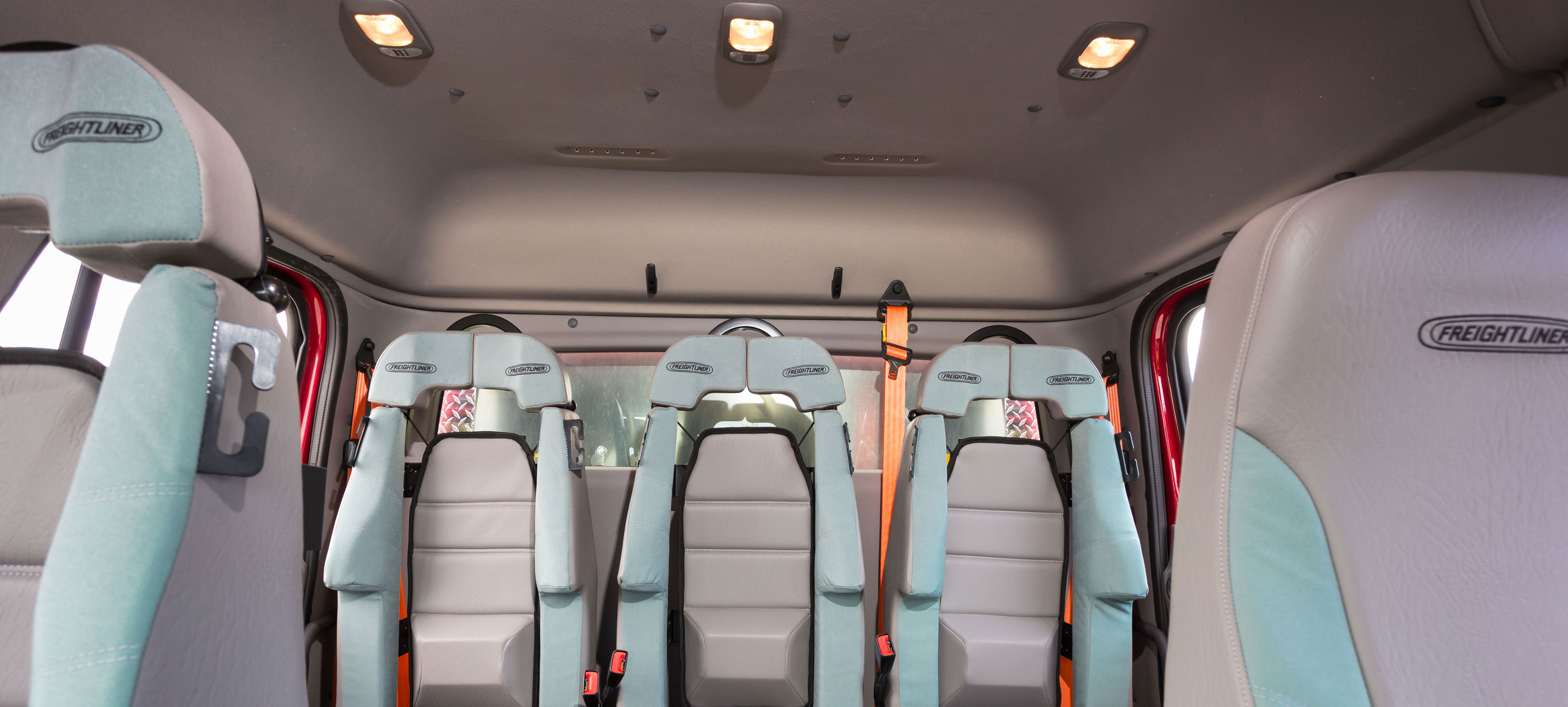 Three tan, rear seats in the back of a Pierce Freightliner commercial chassis with tan interior. 