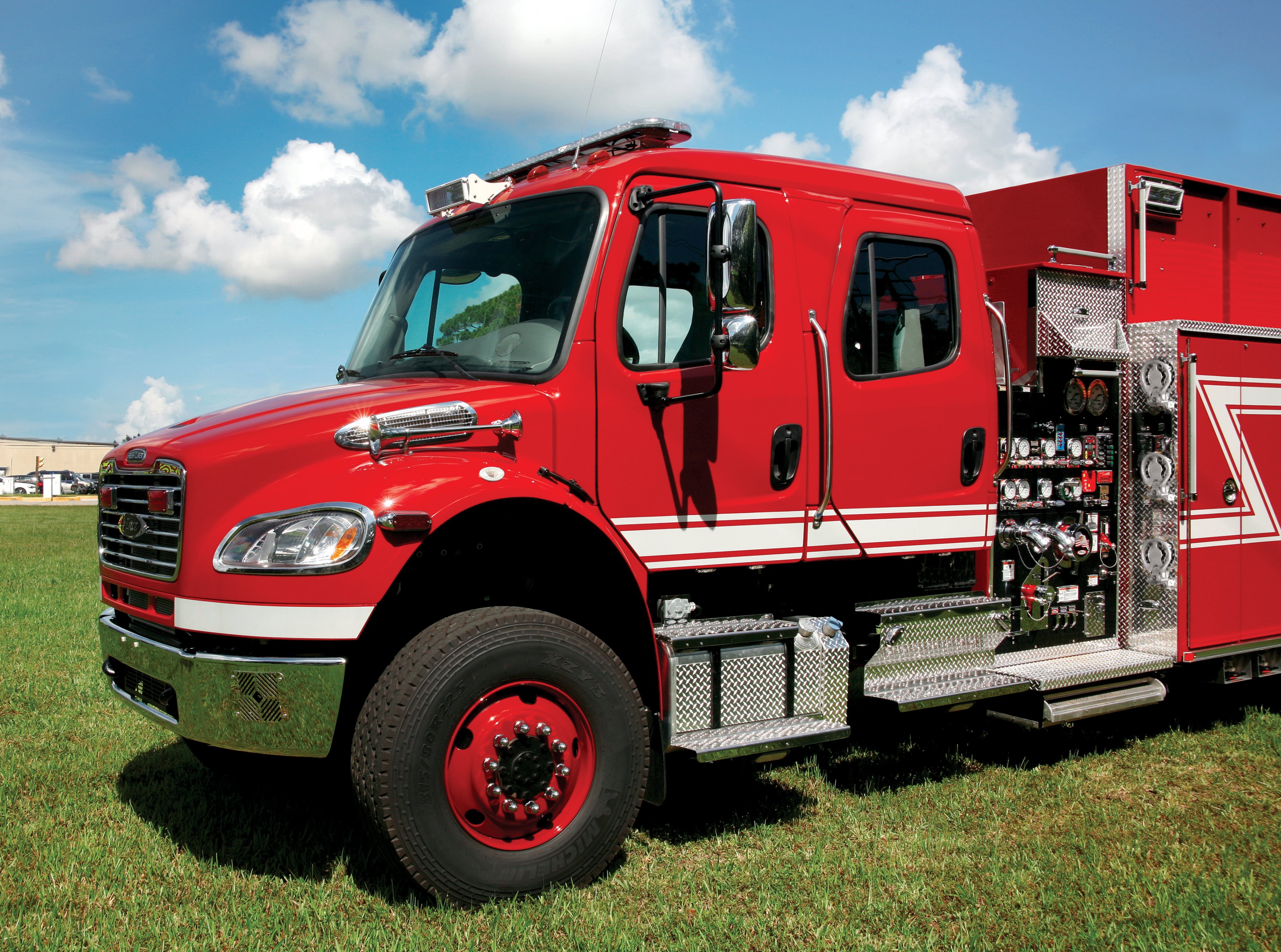 Front drivers side of Pierce Freightliner commercial chassis parked outside on the grass on a sunny day. 