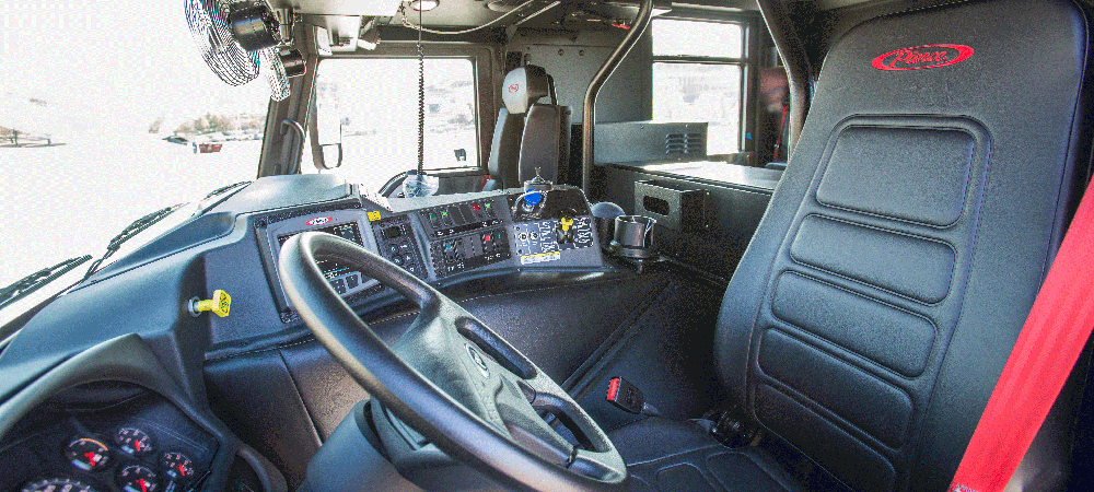 Black leather front drivers side seat and steering wheel in a Pierce custom fire truck. 