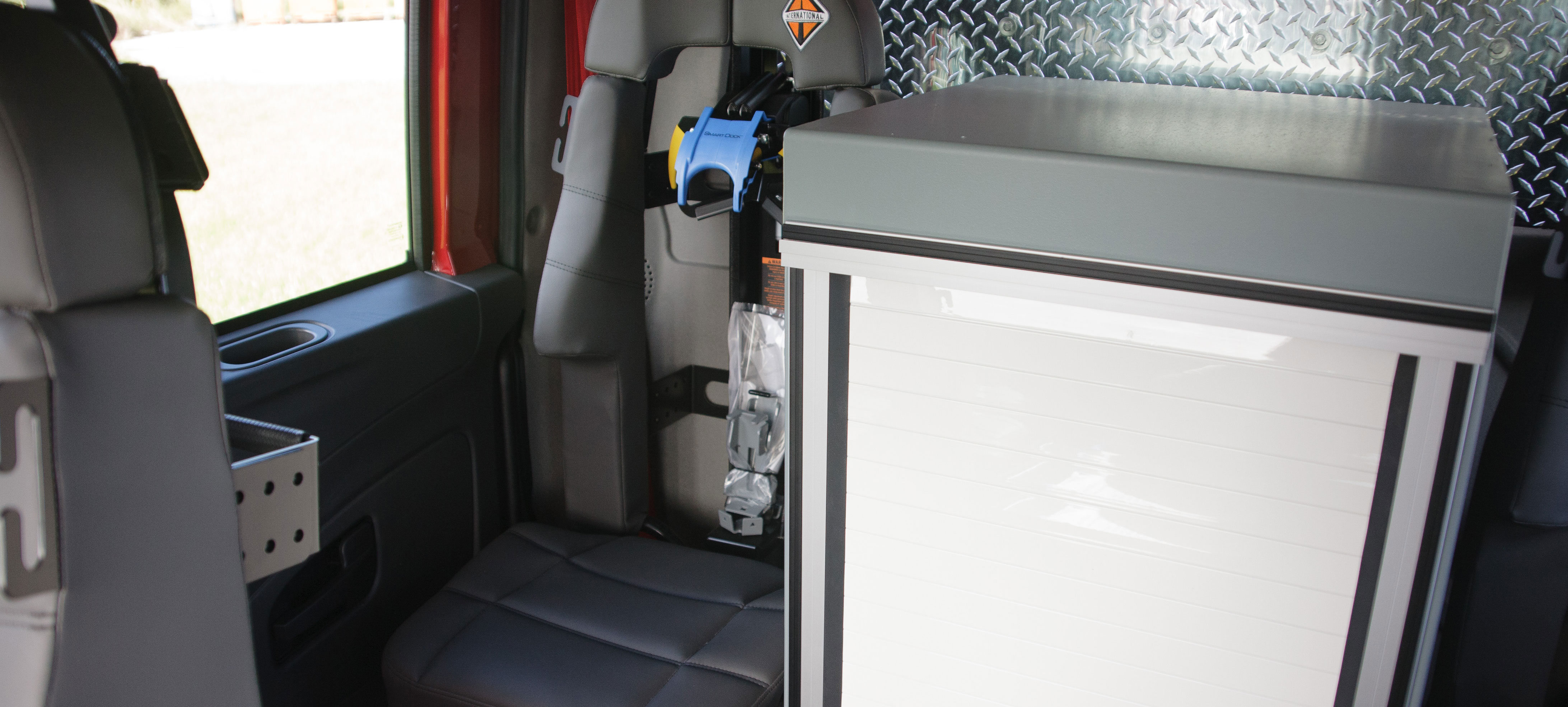 Back rear grey seat and storage on the interior of a Pierce International commercial fire truck chassis cab. 