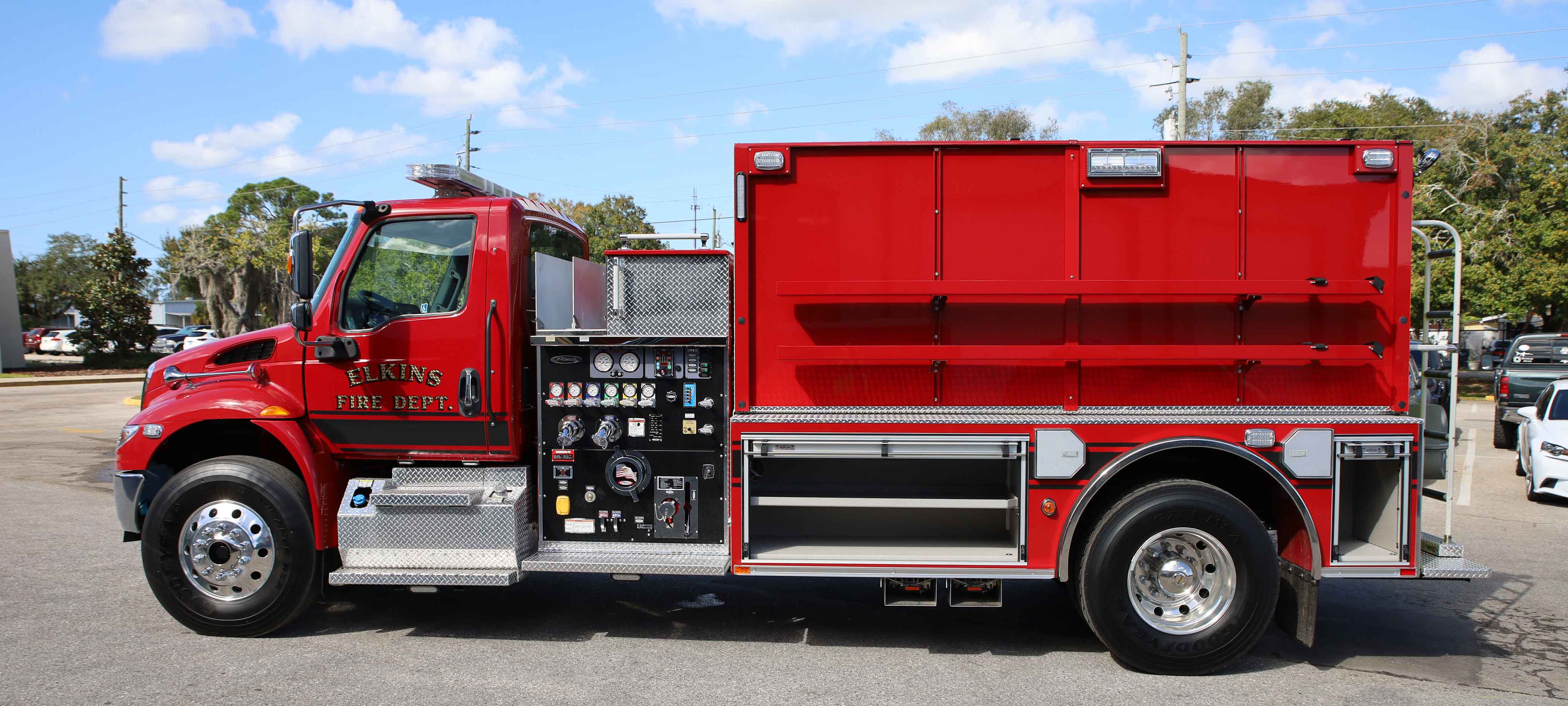 Exterior drivers side of a Pierce International commercial fire truck chassis drivers side extended cab pumper parked outside in a parking lot on a sunny day. 