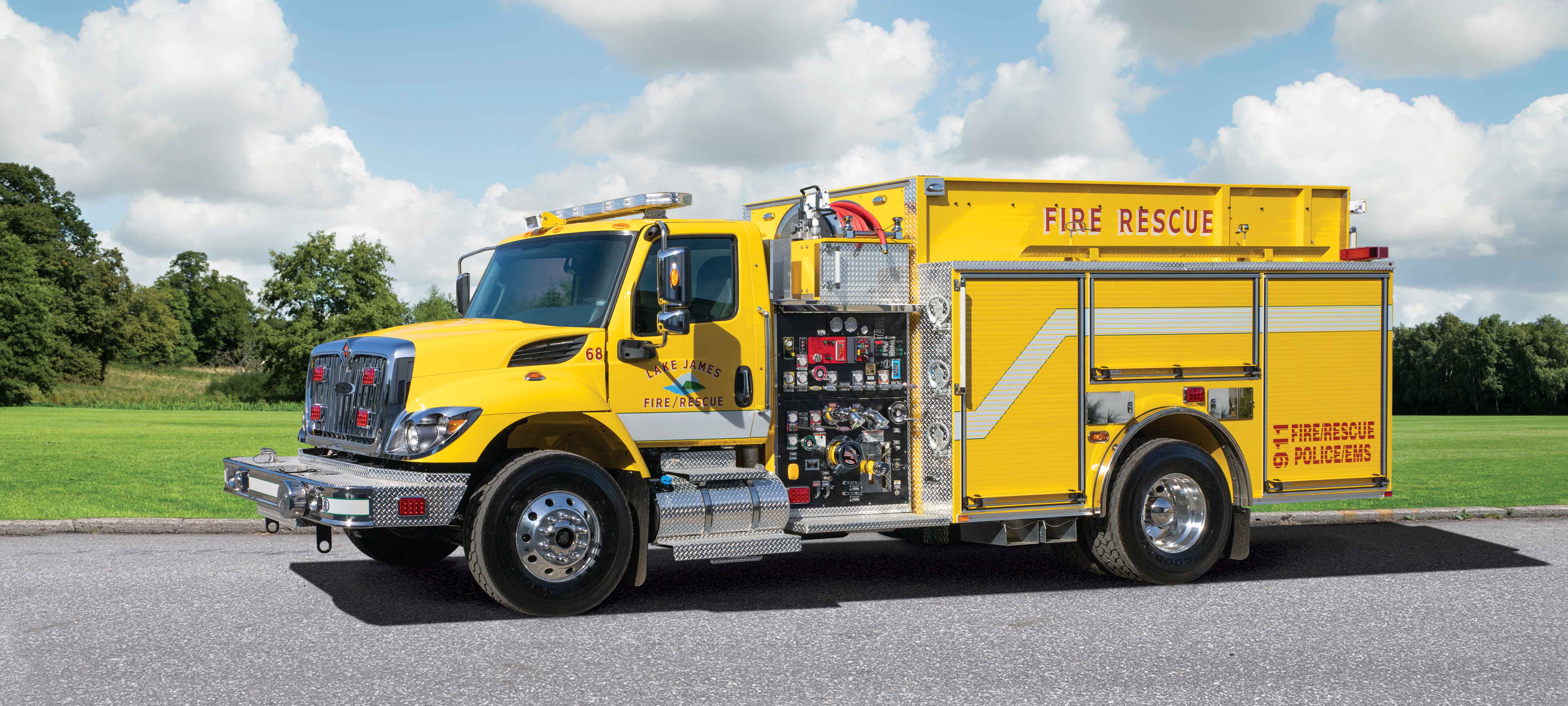 Pierce International Commercial Fire Truck Chassis parked outside on the road on a sunny day surrounded by trees. 