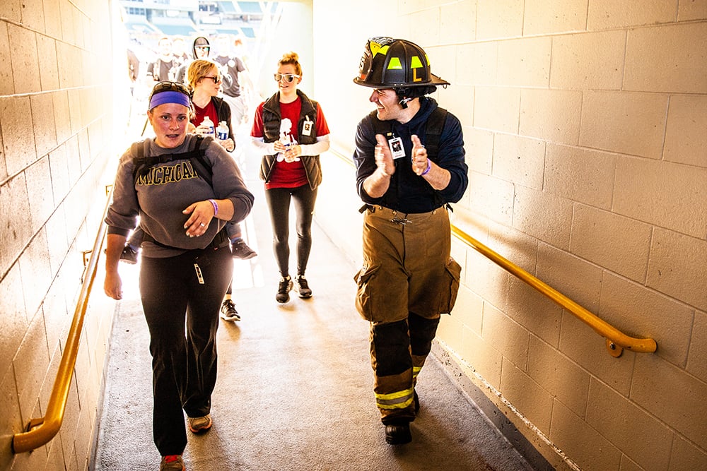 A firefighter and three women walking through the tunnel at Lambeau Field at the Pierce Manufacturing 9/11 Memorial Stair Climb Event.