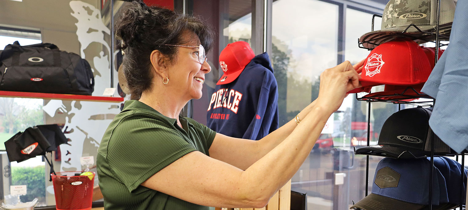 A woman in a merchandise store holding onto a hat.