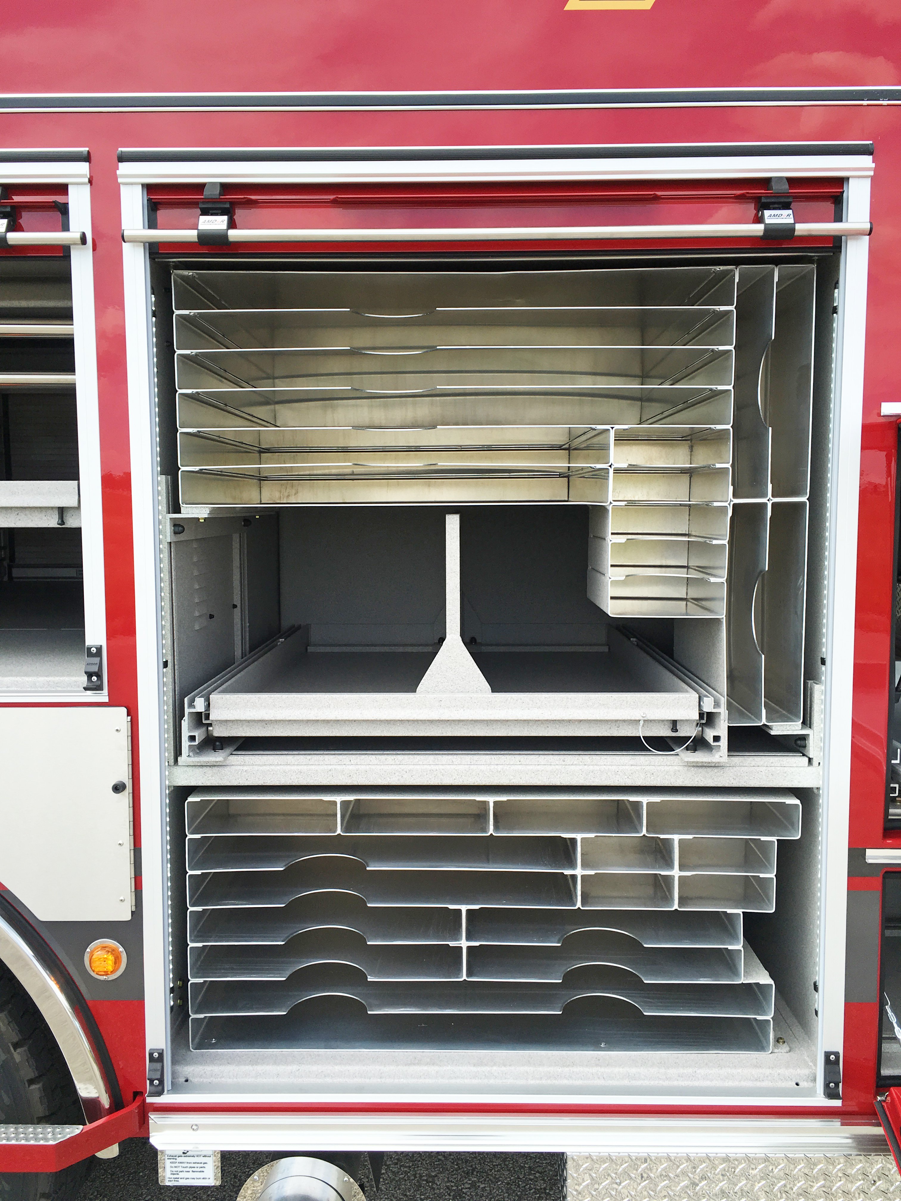 Roll up door open on a Pierce Combination Rescue Fire Truck showing compartment shelving and storage space. 