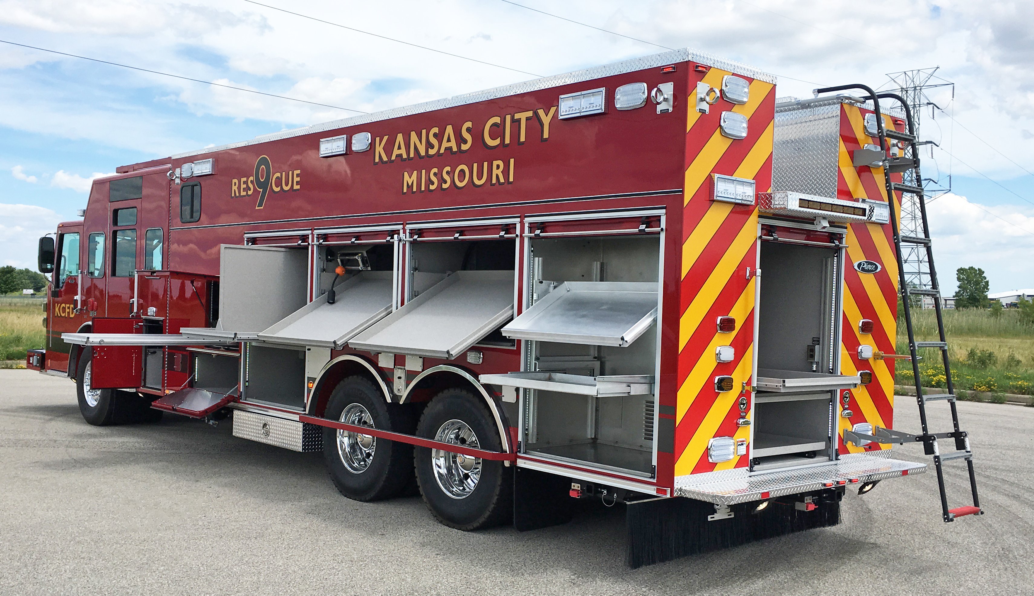 Pierce Combination Rescue Fire Truck parked outside in a parking lot with Officer’s side and rear compartments open showing storage space. 