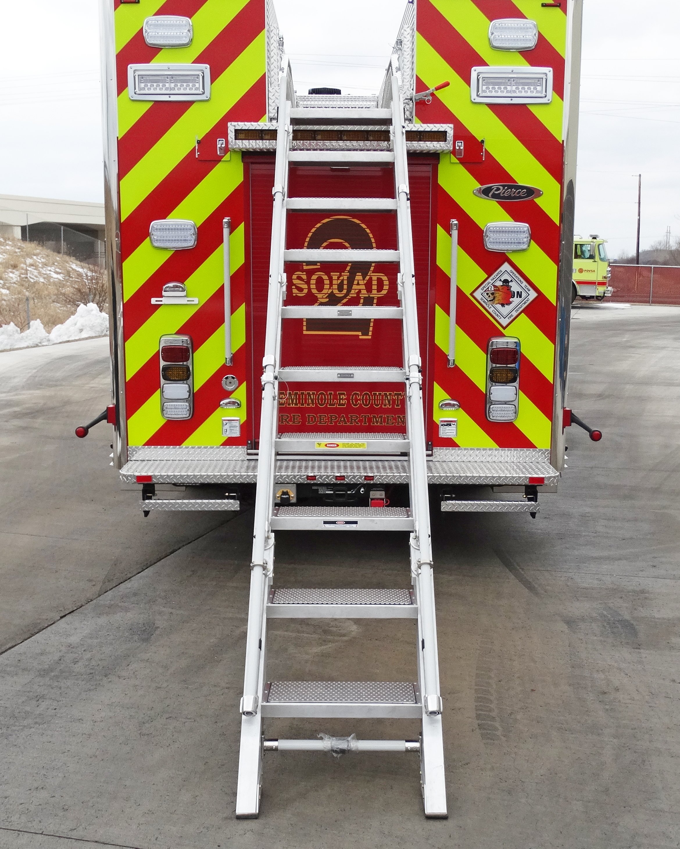 Rear of a Pierce Combination Rescue Fire Truck parked outside in a parking lot with the ladder extended. 