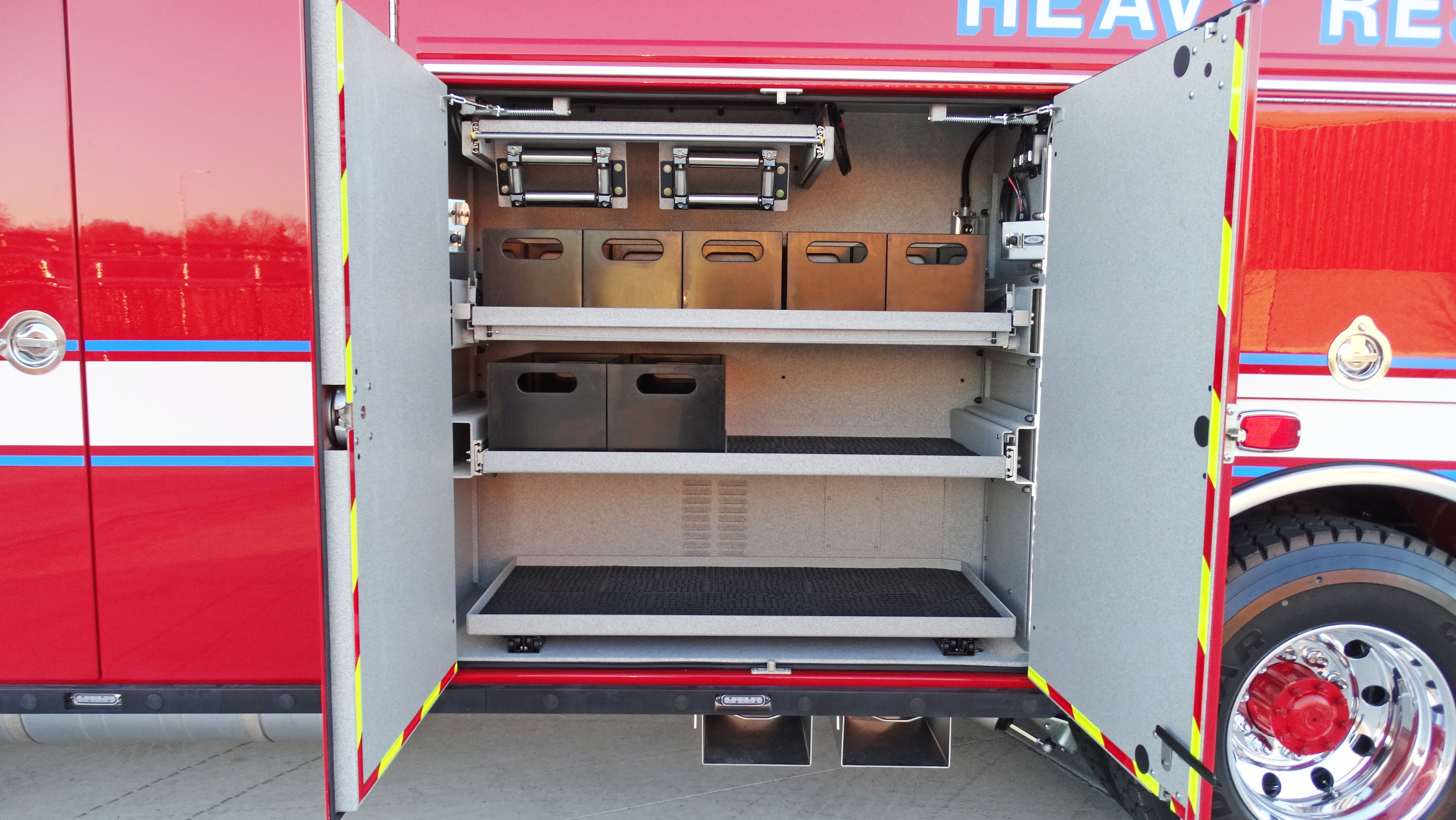 Pierce Combination Rescue Fire Truck parked outside with side compartments open showing storage shelves. 