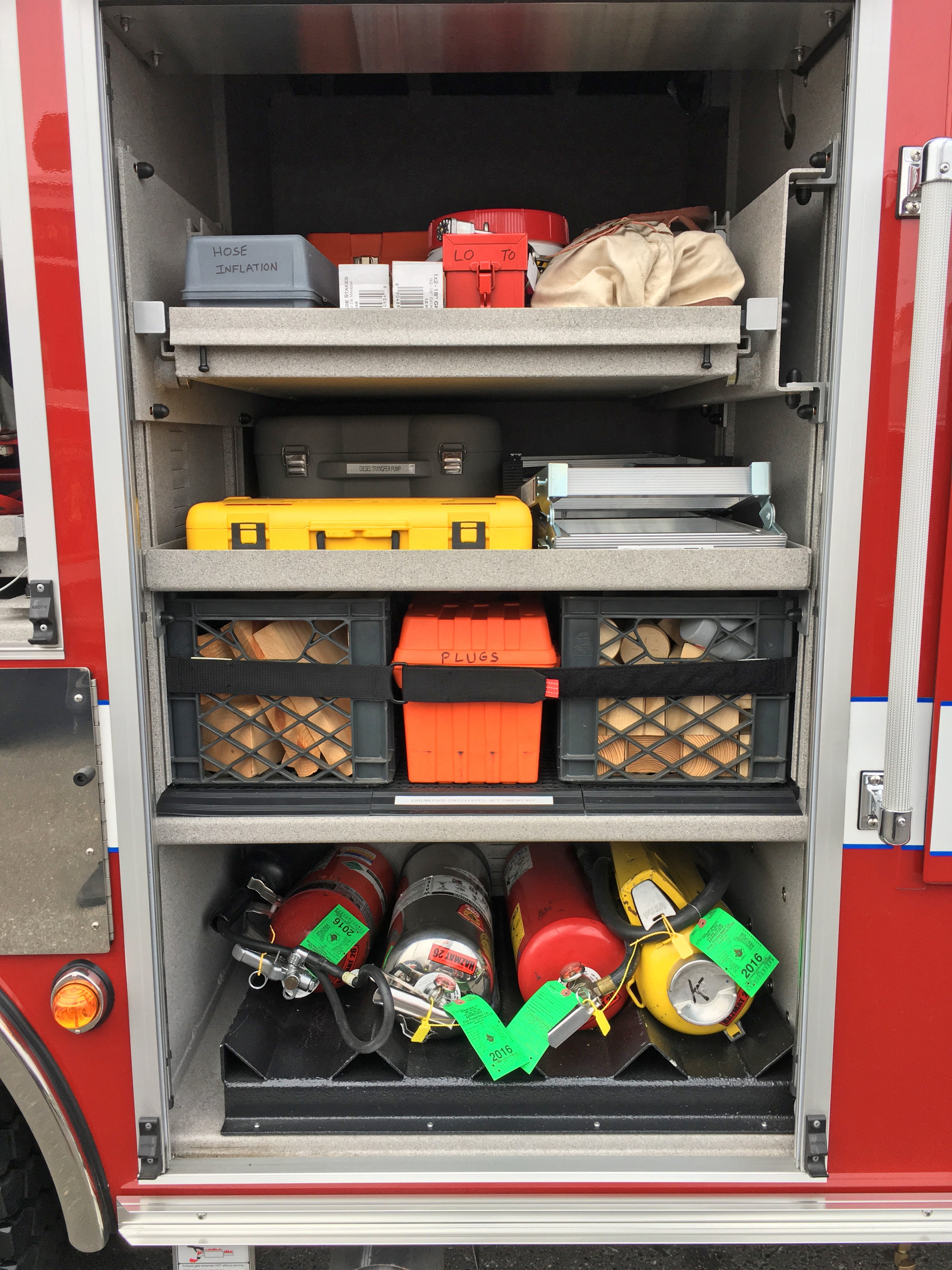 Roll up door on a Pierce Combination Rescue Fire Truck open showing the shelves and storage space.  