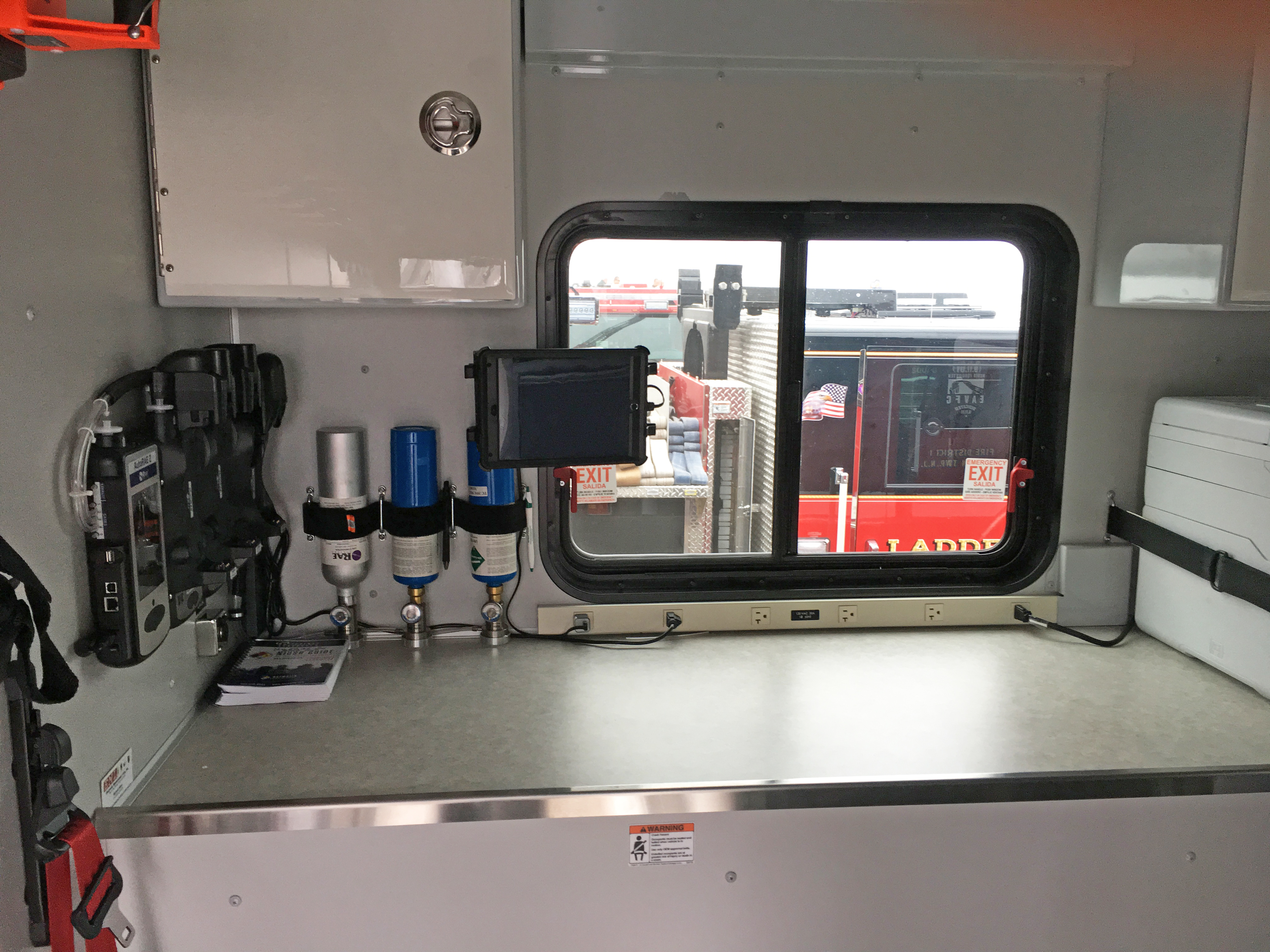 Interior layout of a Pierce Combination Rescue Fire Truck with a storage compartment to the left and a window above a countertop. 