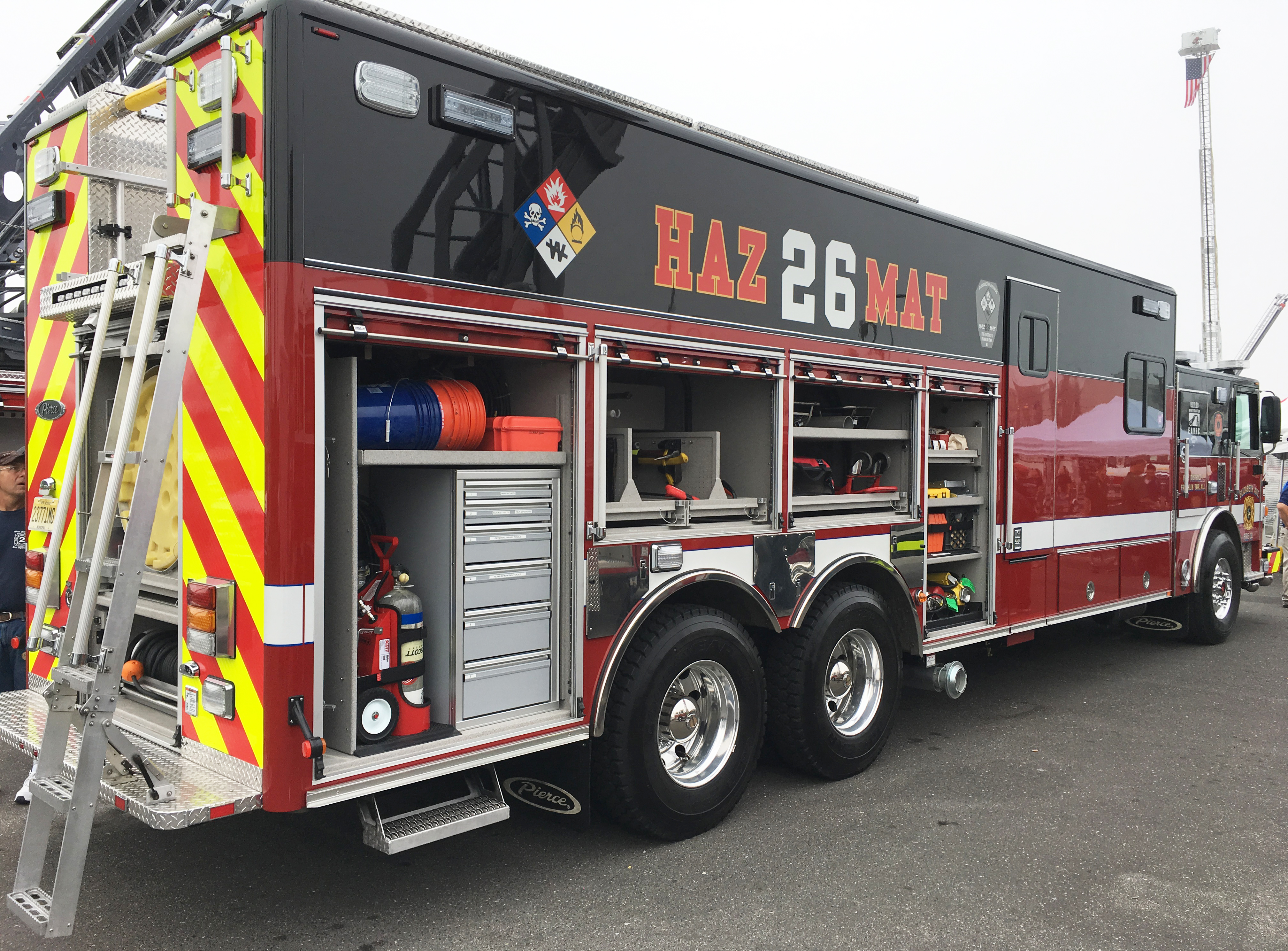 Passenger’s side of a Pierce Combination Rescue Fire Truck with side compartments open showing storage space.  