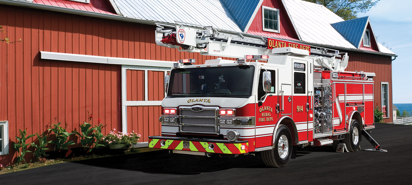 Pierce Heavy-duty Sky-Boom Aerial Tower Fire Truck parked outside in front of fire station. 