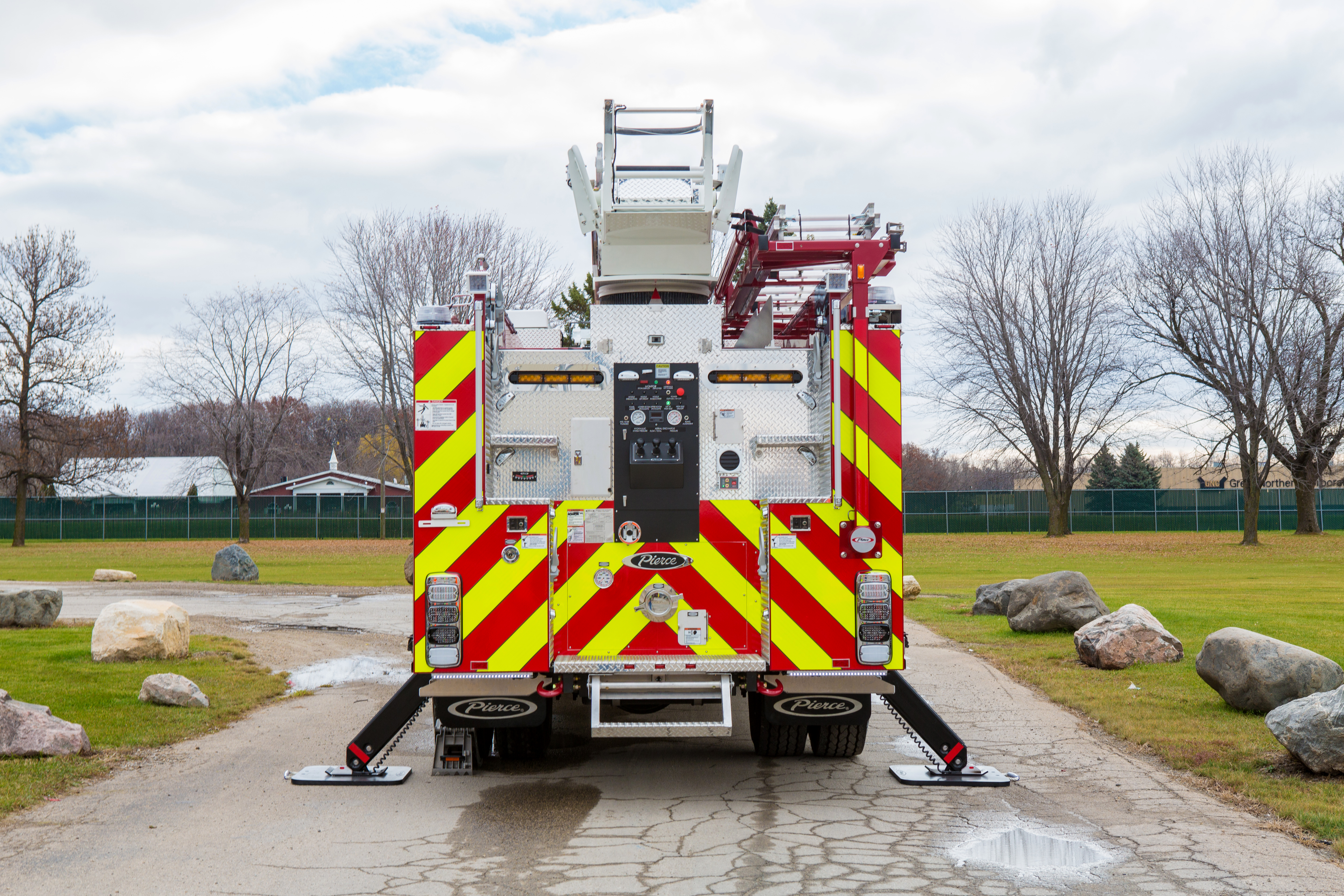 Pierce Heavy-Duty Sky-Boom Aerial fire truck parked outside with stabilizers on the ground on both sides of the apparatus. 