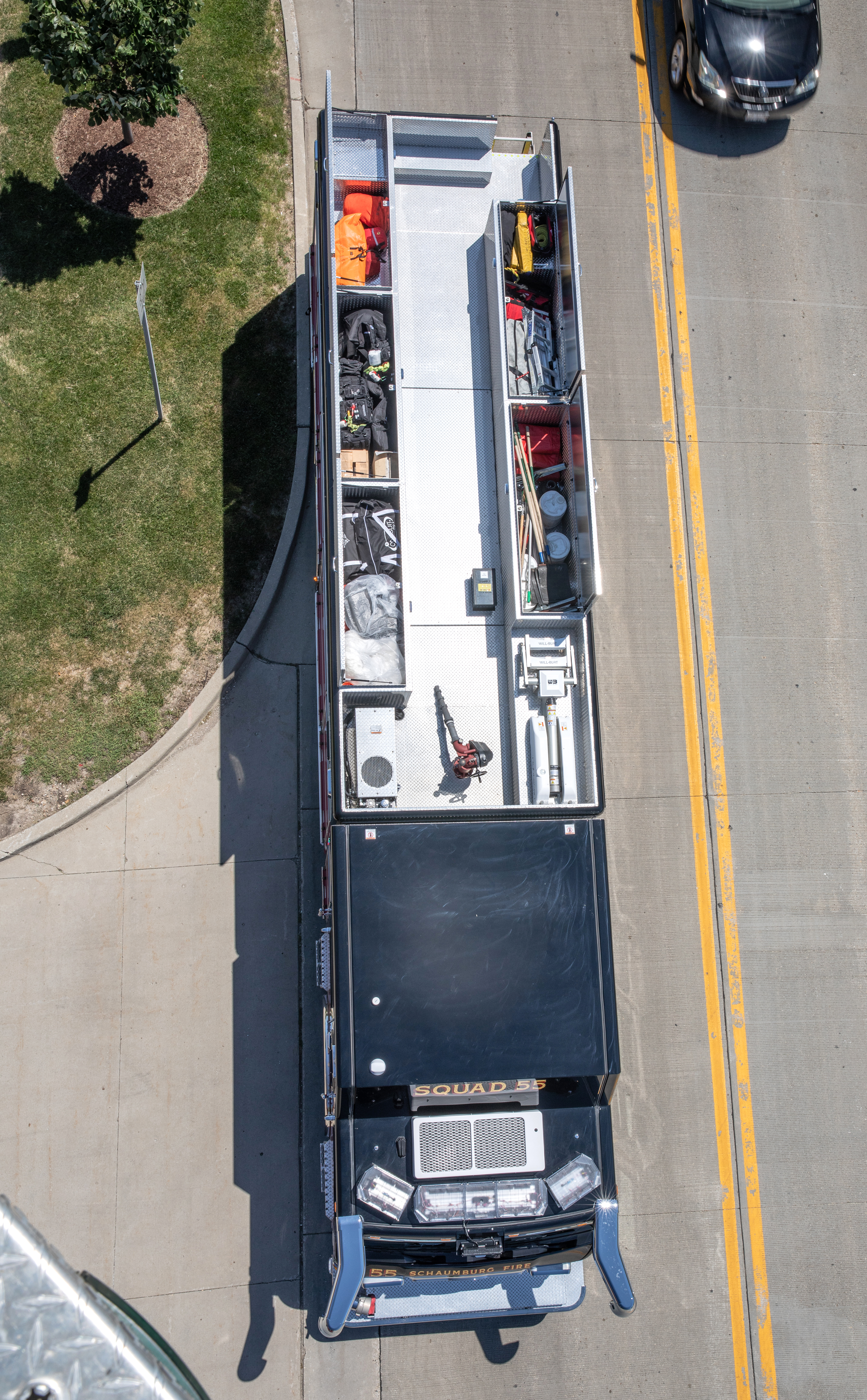 Aerial view of a Pierce Non-Walk-In Rescue Fire Truck parked outside on the street with compartments on the left and right side atop of the apparatus. 