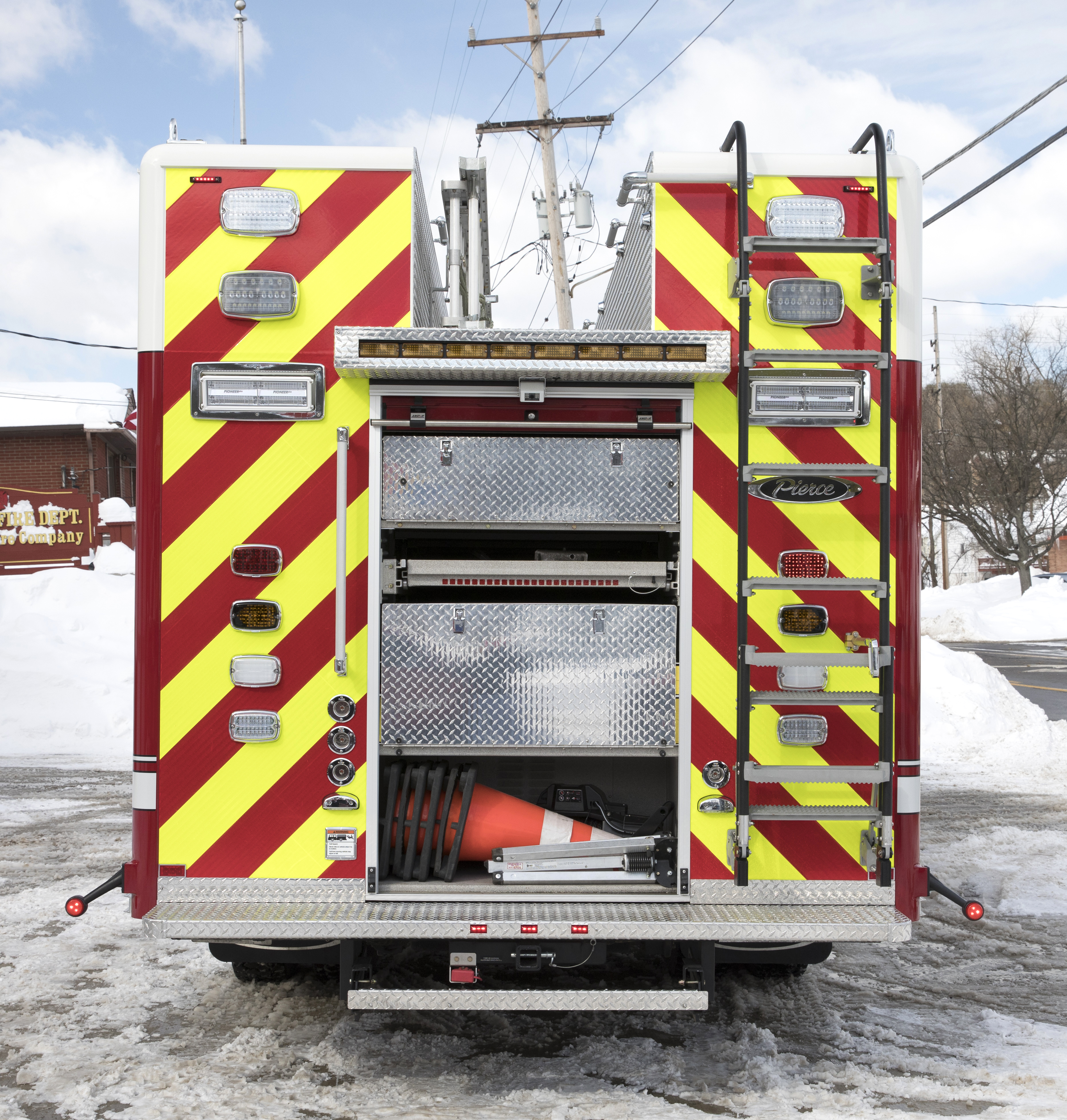 Rear of a Pierce Non-Walk-In Rescue Fire Truck with compartment open showing rear storage and hose bed. 