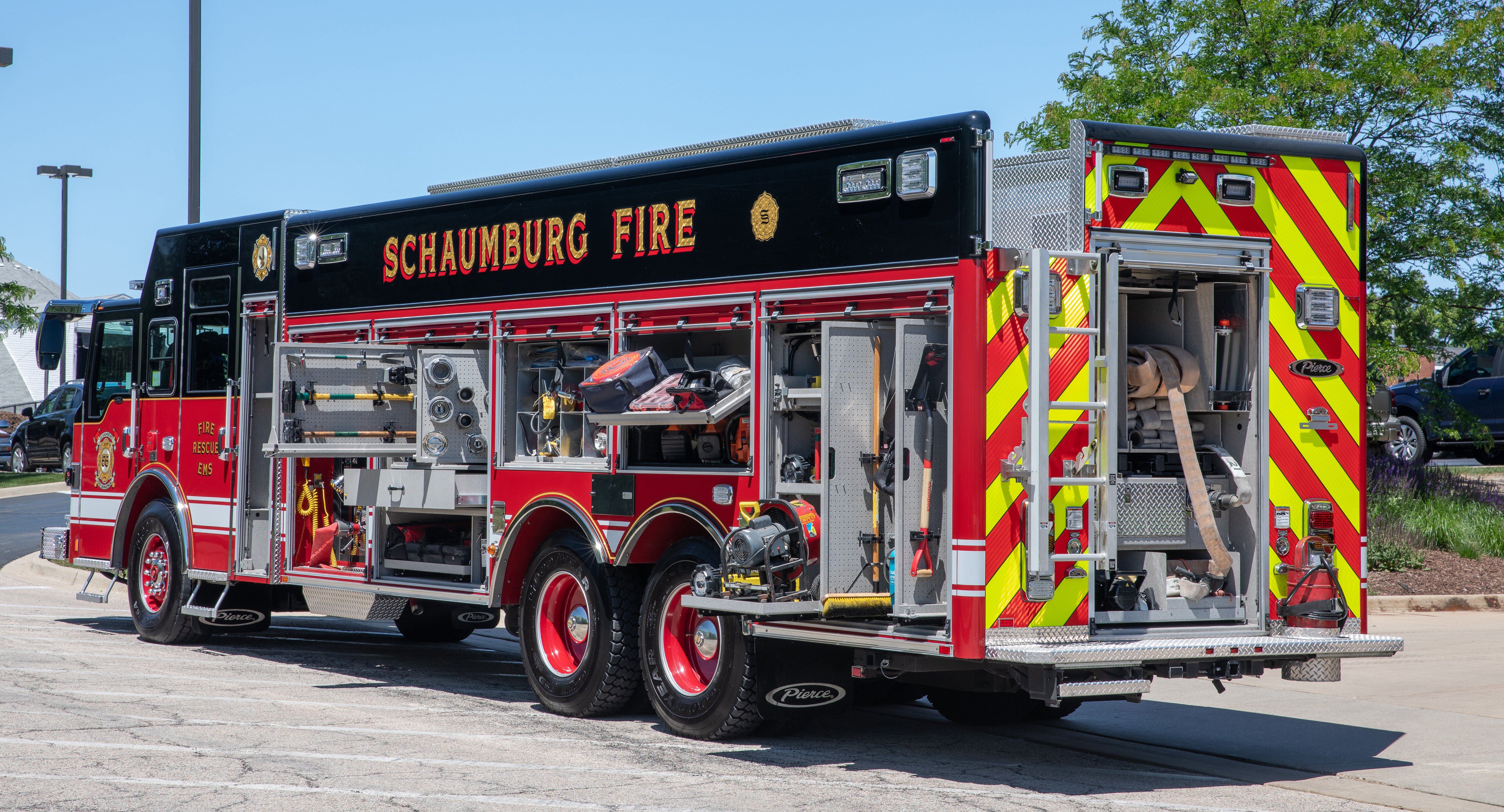 Officer’s side of a Pierce Non-Walk-In Rescue Fire Truck parked outside with side and rear compartments open showing storage space. 