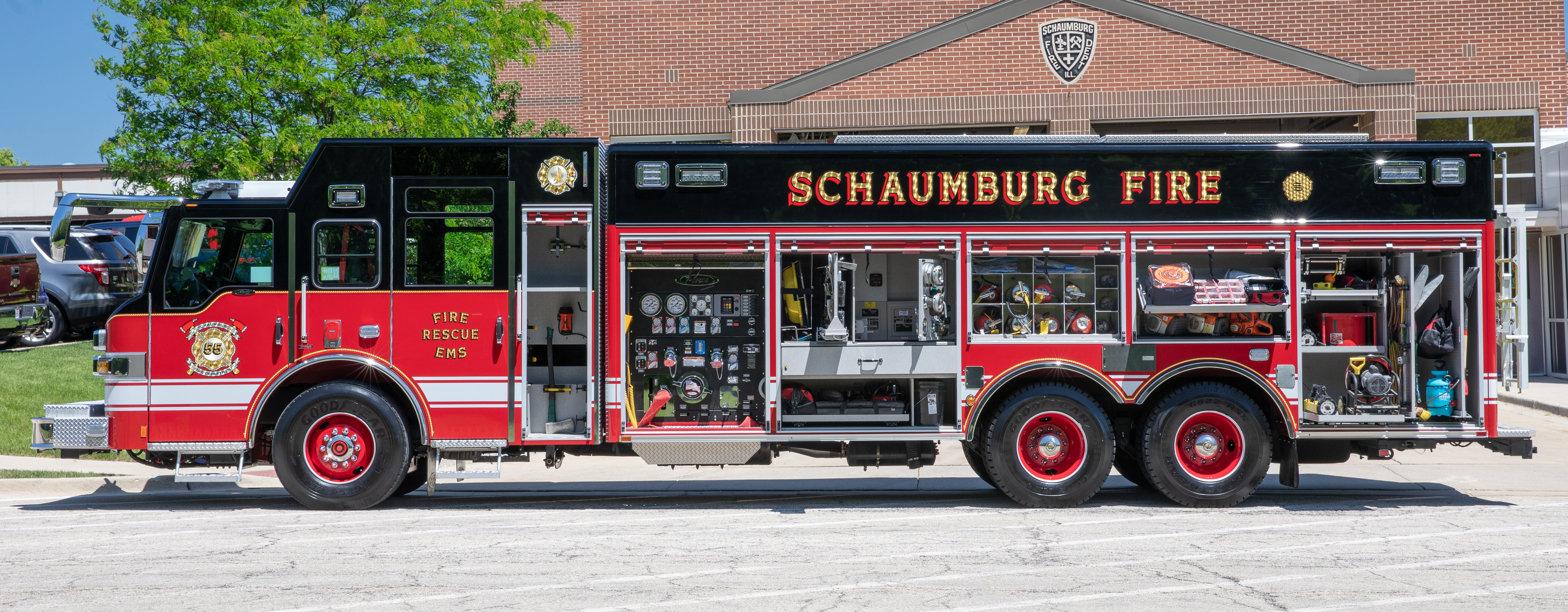 Pierce Non-Walk-In Rescue Fire Truck parked outside in front of a fire station with Officer’s side compartments open showing storage space. 