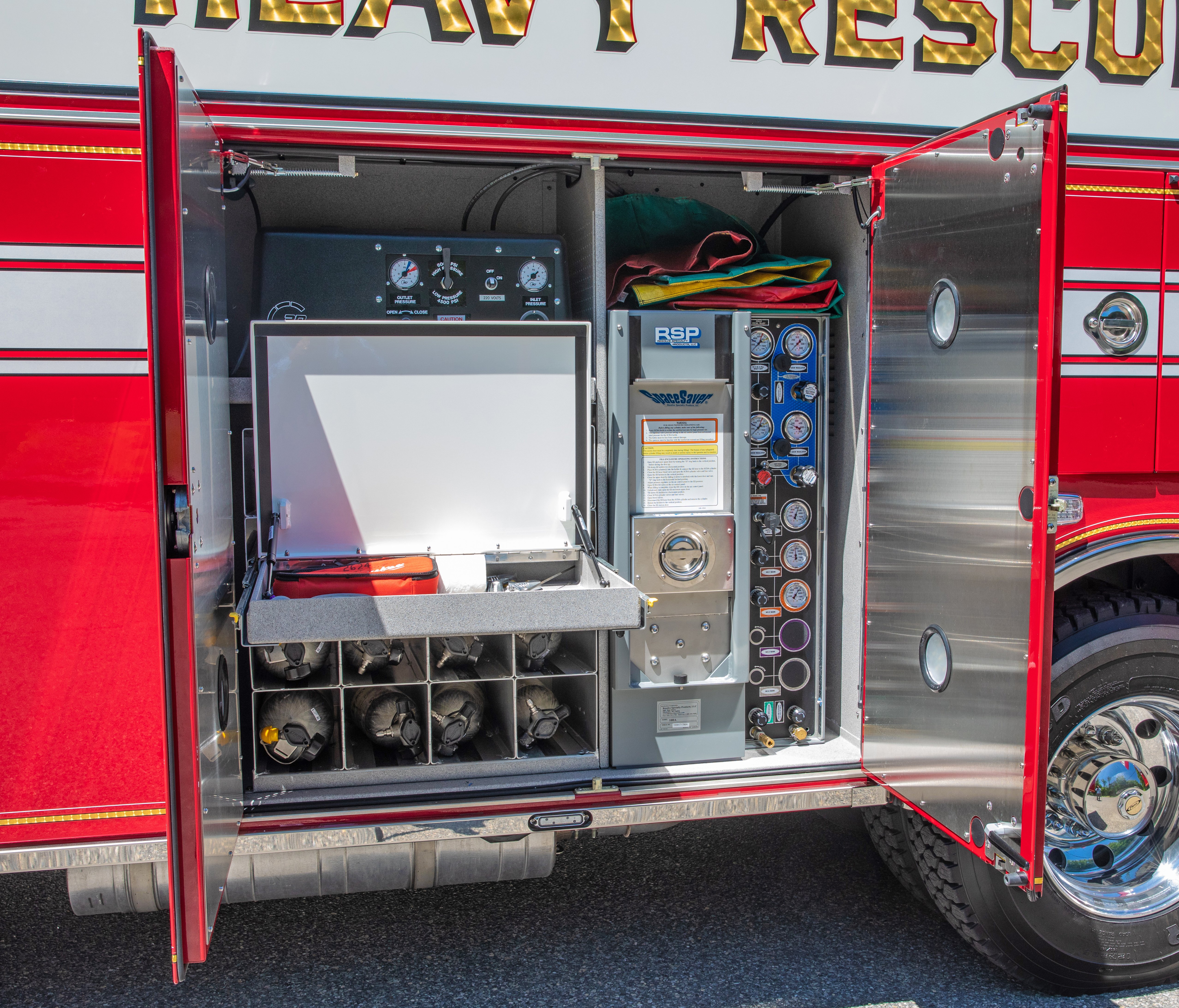 The side of a Pierce Walk-In Heavy-Duty Fire Truck with lap doors open showing storage space and equipment. 