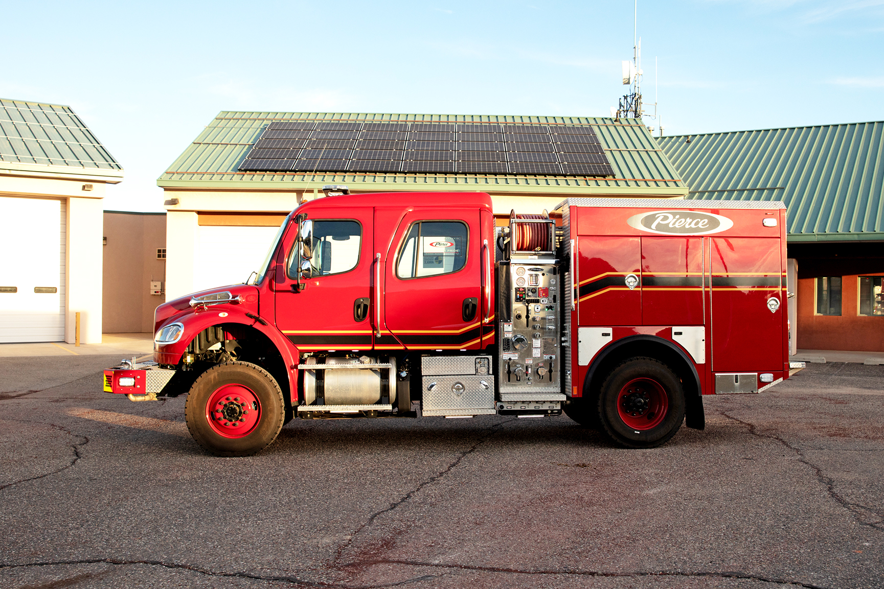 Officer’s side of a Pierce BX™ Wildland Fire Truck parked outside on a sunny day in front of a building.  