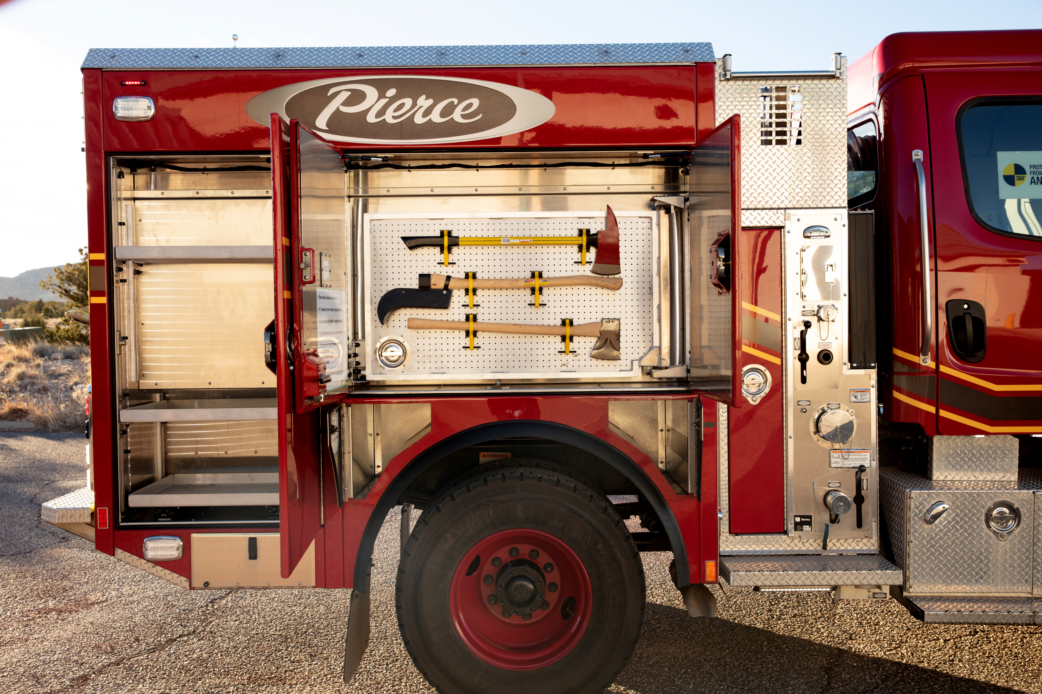 Passengers side of a Pierce BX™ Wildland Fire Truck with side compartments open showing storage space. 