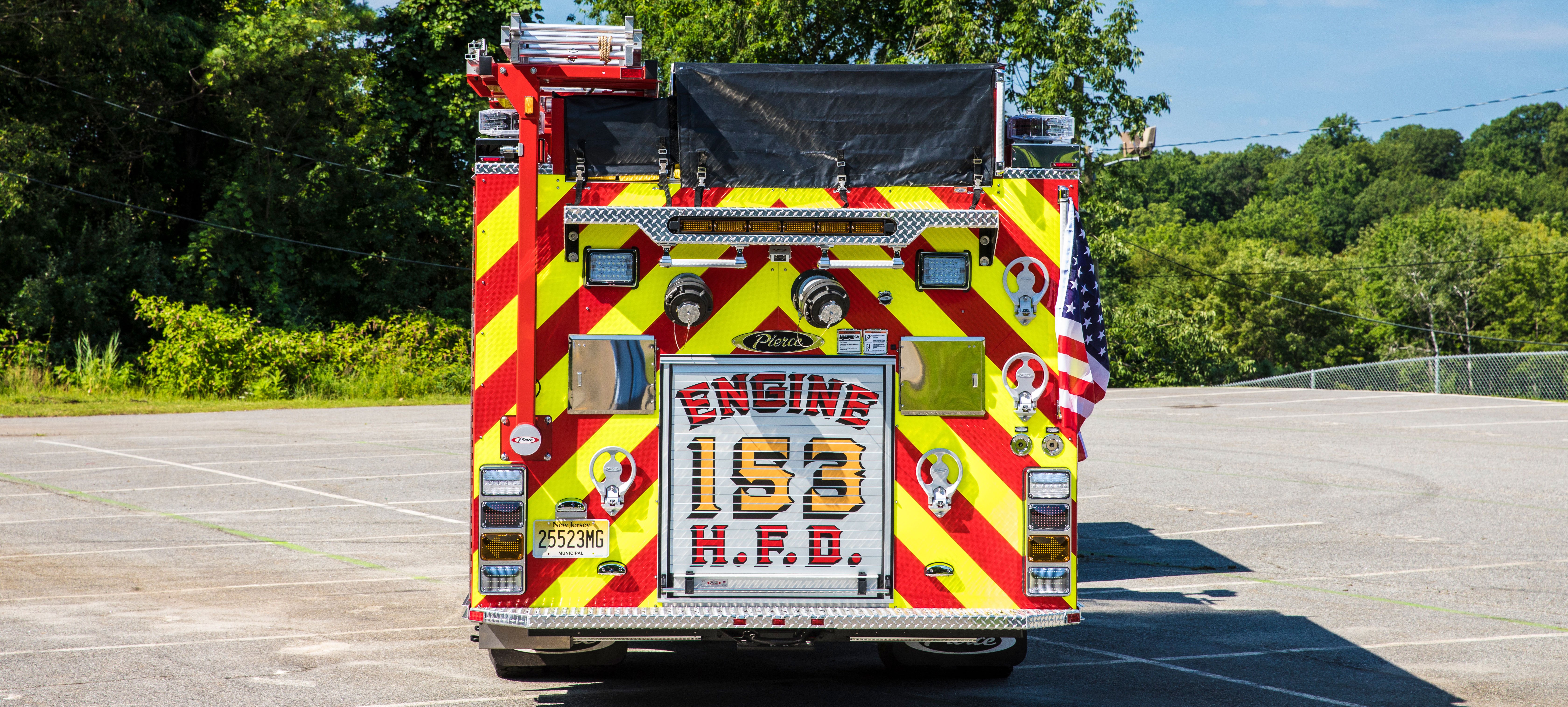 Rear of a Pierce Pumper Fire Truck parked outside in a parking lot on a sunny day.  