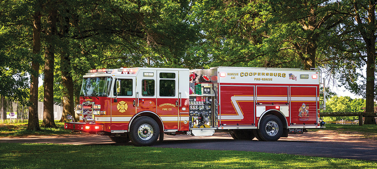 Heavy-Duty Rescue Pumper on sunny day parked in trees