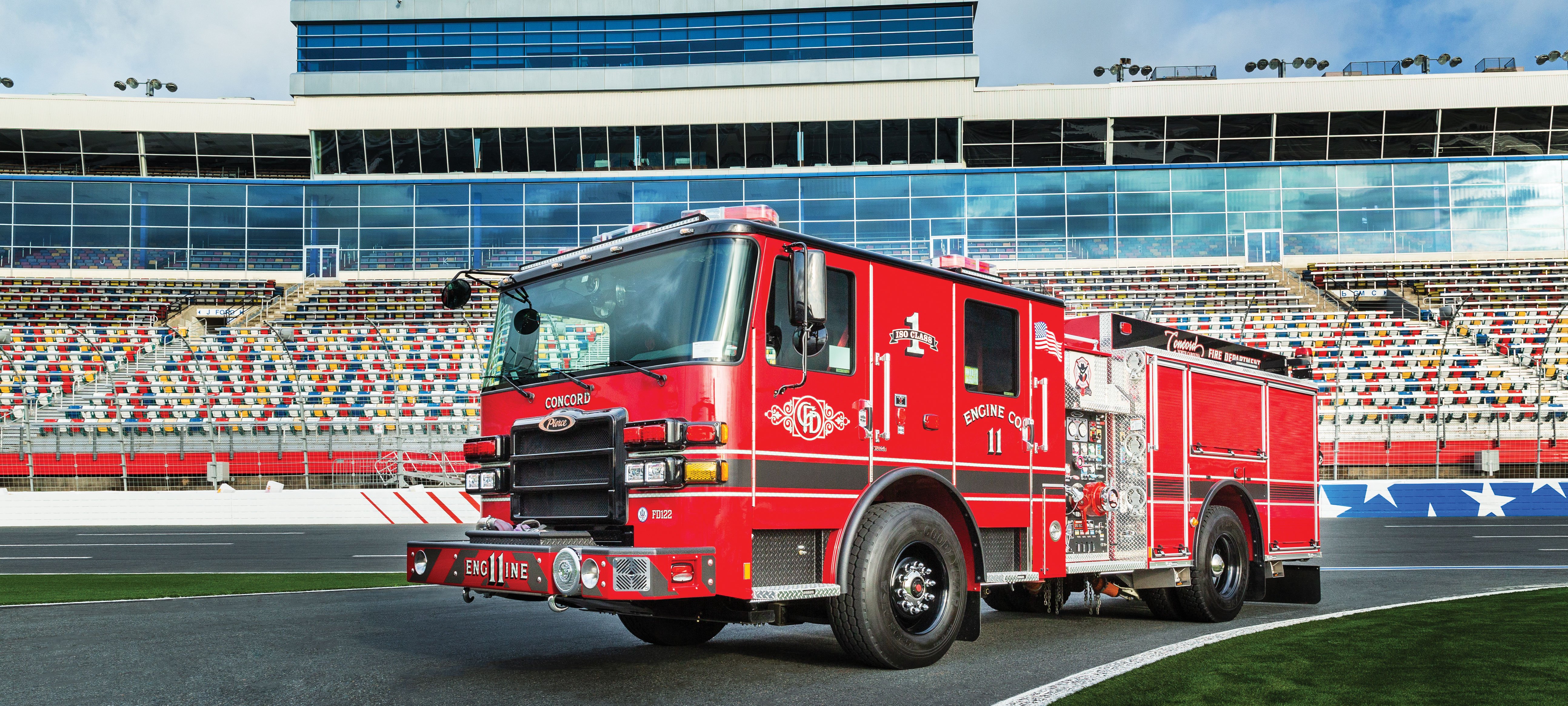 Pierce Pumper Fire Truck parked outside in a racetrack stadium.  