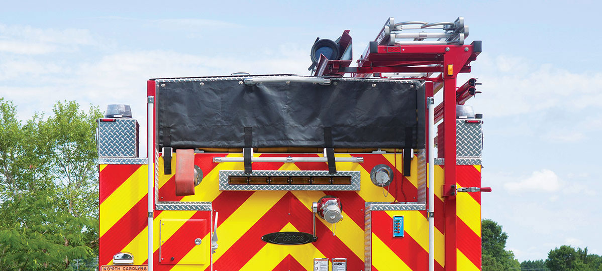 Pierce Fire Truck Pumper parked outside with an Aluminum Vinyl Netted Roll Up Cover on rear of apparatus. 