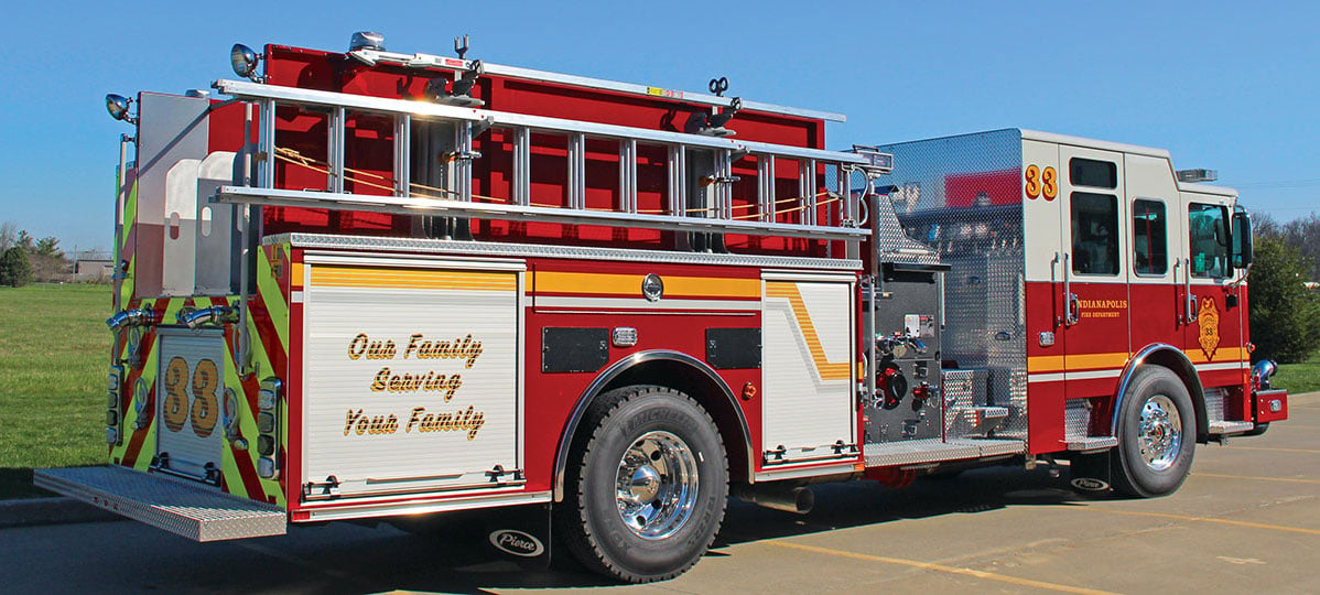 Pierce Pumper Fire Truck with rear dropdown ladder storage on rear of the apparatus parked outside in a parking lot on a sunny day. 