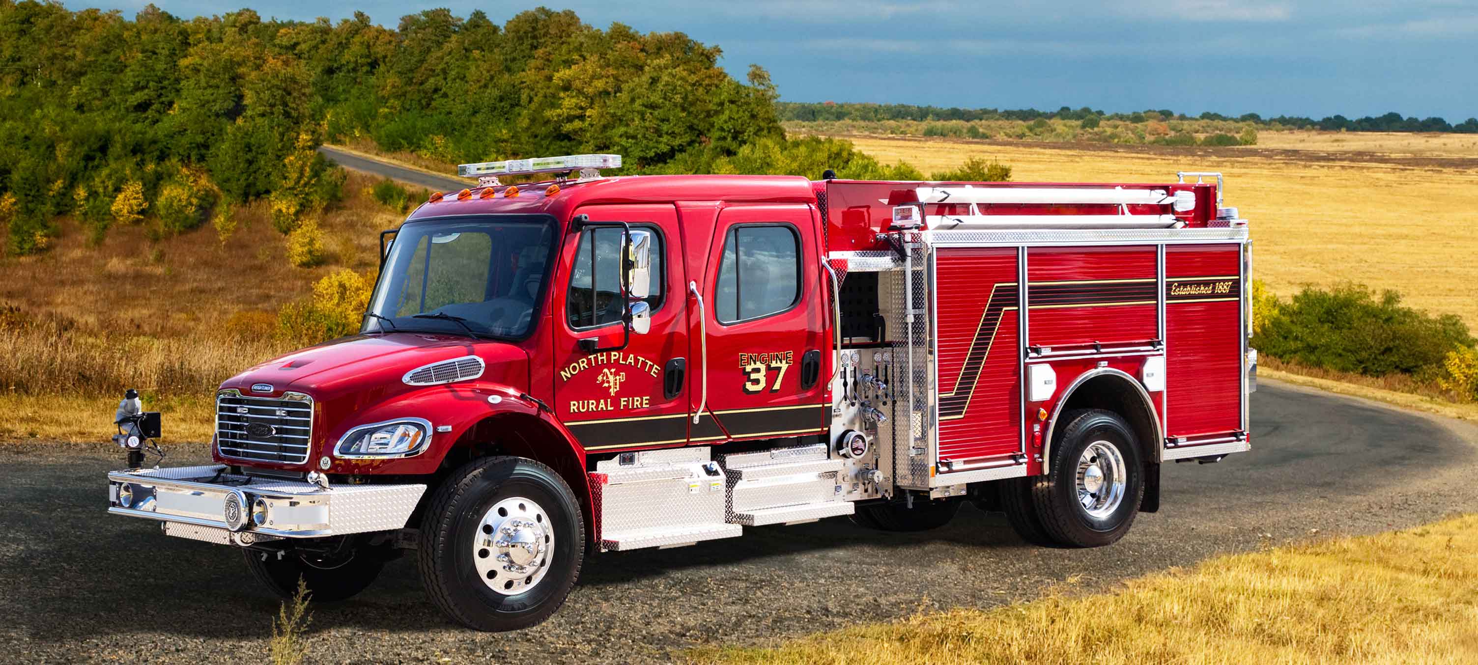 Pierce Pumper Responder Fire Truck parked outside near a field on a sunny day. 