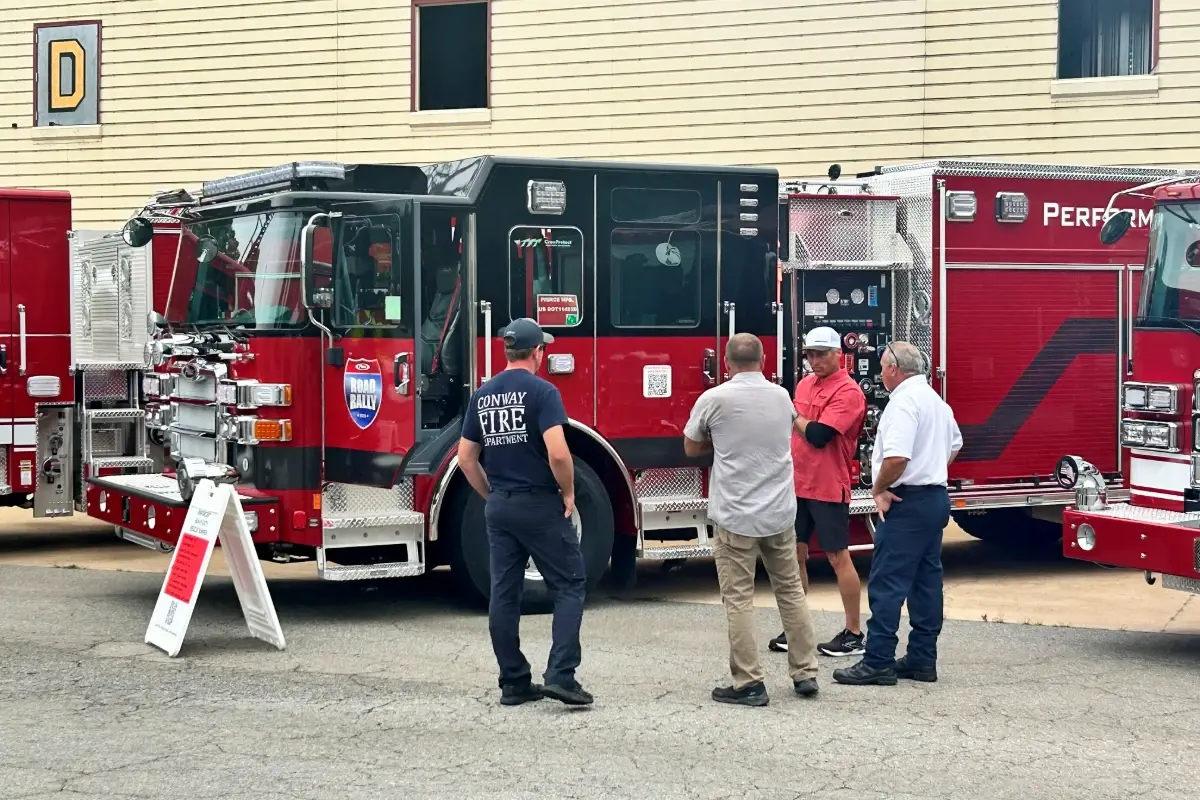 Firefighters discuss a custom Pierce fire engine at a Pierce Road Rally showcase event.