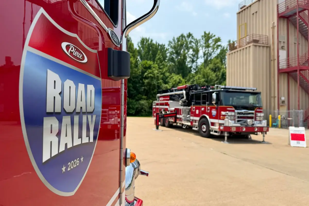 A Pierce fire truck with a 2026 Road Rally shield decal and another truck parked in the background.