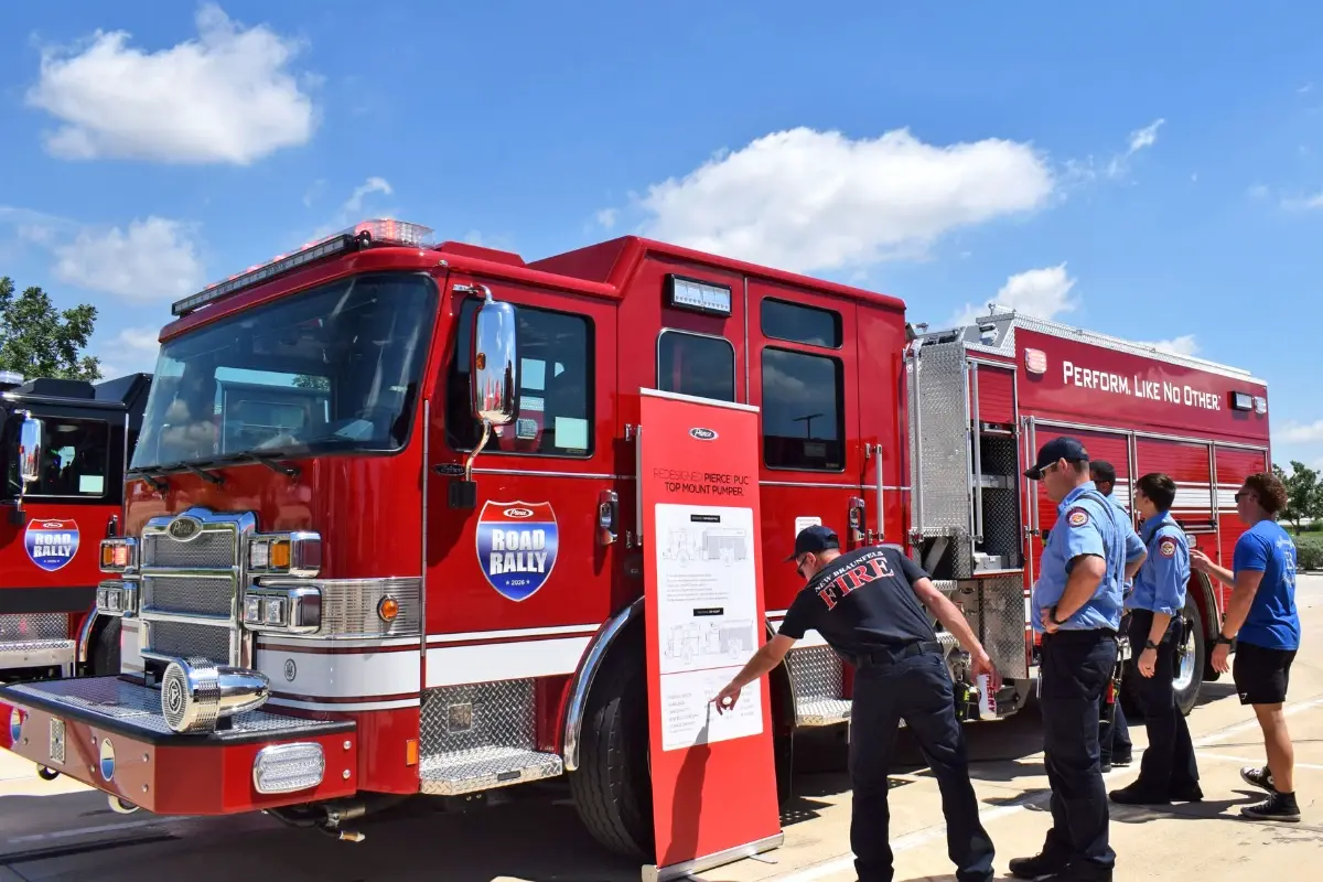 Firefighter pointing at a Pierce top-mount pumper fire truck specification banner at the 2026 Road Rally.