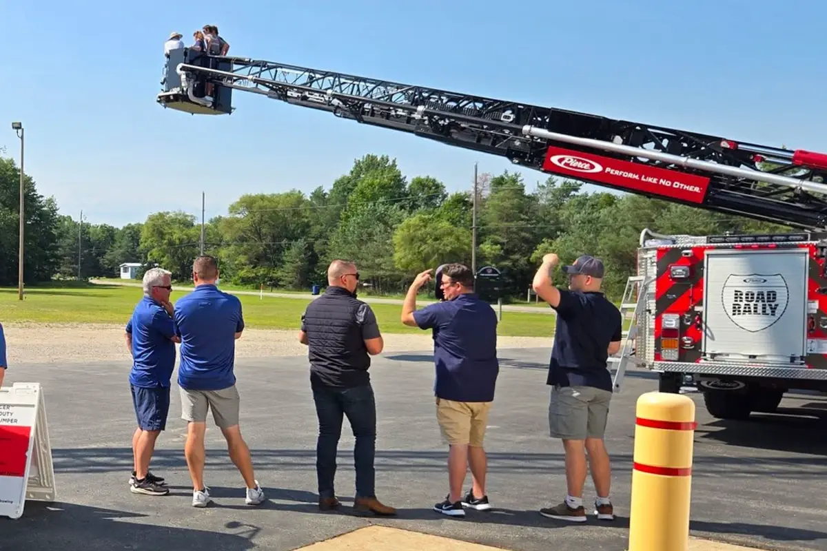 Attendees observe a Pierce Manufacturing aerial fire truck demonstration at a Road Rally event.