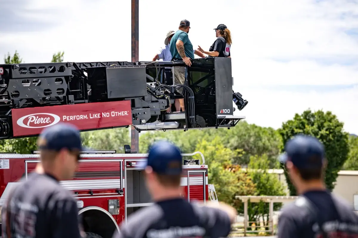Firefighters watch a demonstration on a Pierce Ascendant 100-foot aerial tower platform.